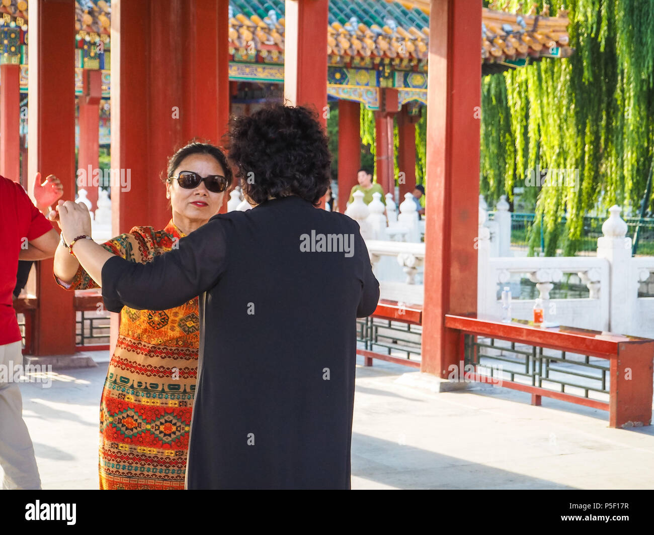 Pechino, Cina - Settembre 2017: due donne anziane a ballare come un paio di padiglioni in parco Beihai durante il tramonto Foto Stock