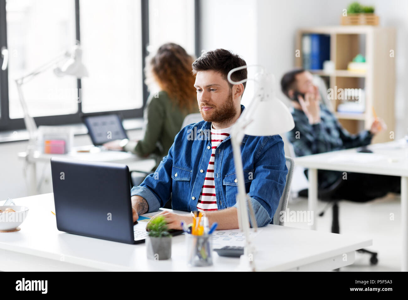 Uomo creativo con il computer portatile lavorando in ufficio Foto Stock