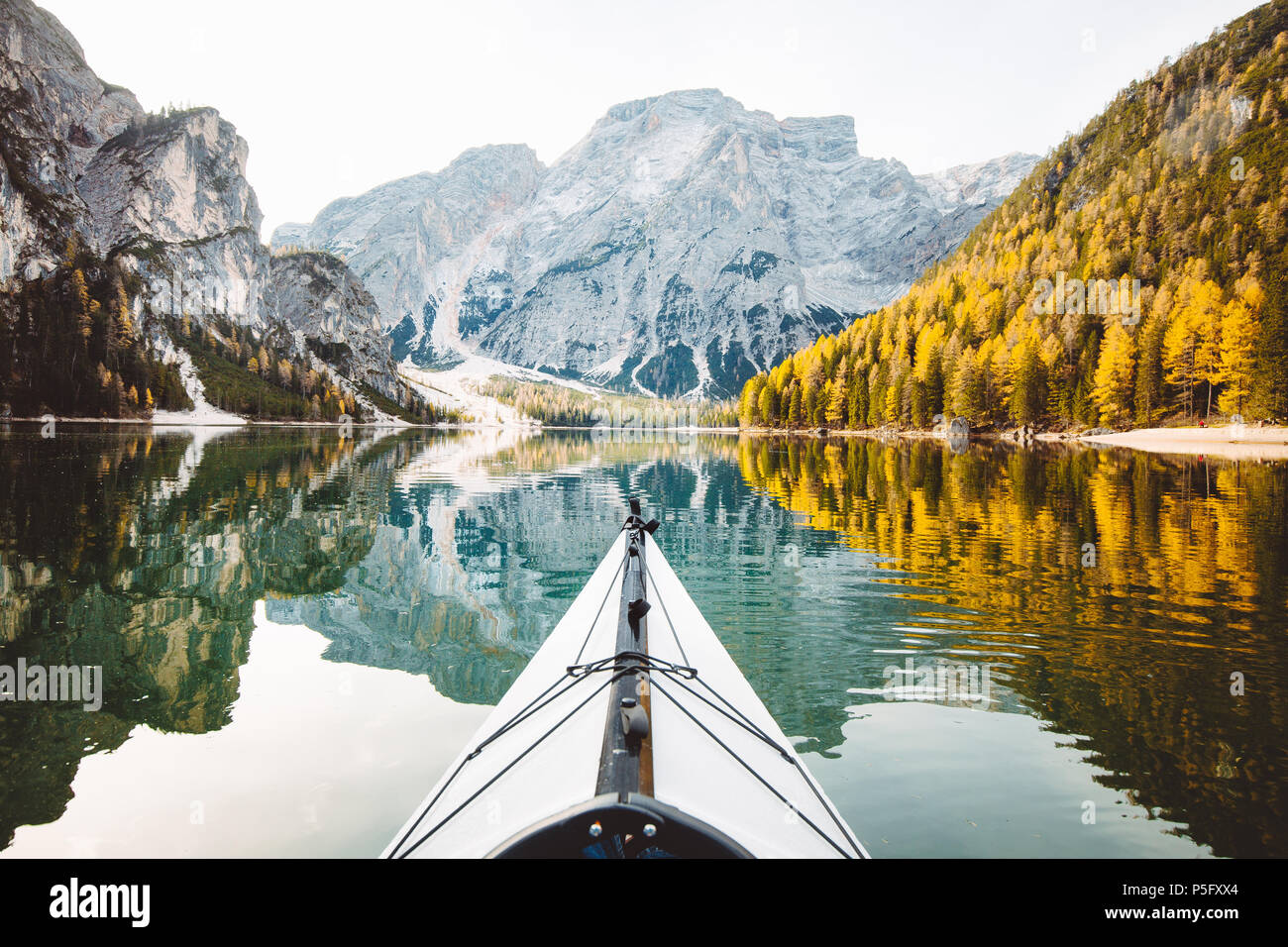 Bellissima vista del kayak su di un lago calmo con sorprendente riflessioni di picchi di montagna e gli alberi con giallo fogliame di autunno in autunno, il Lago di Braies, Italia Foto Stock