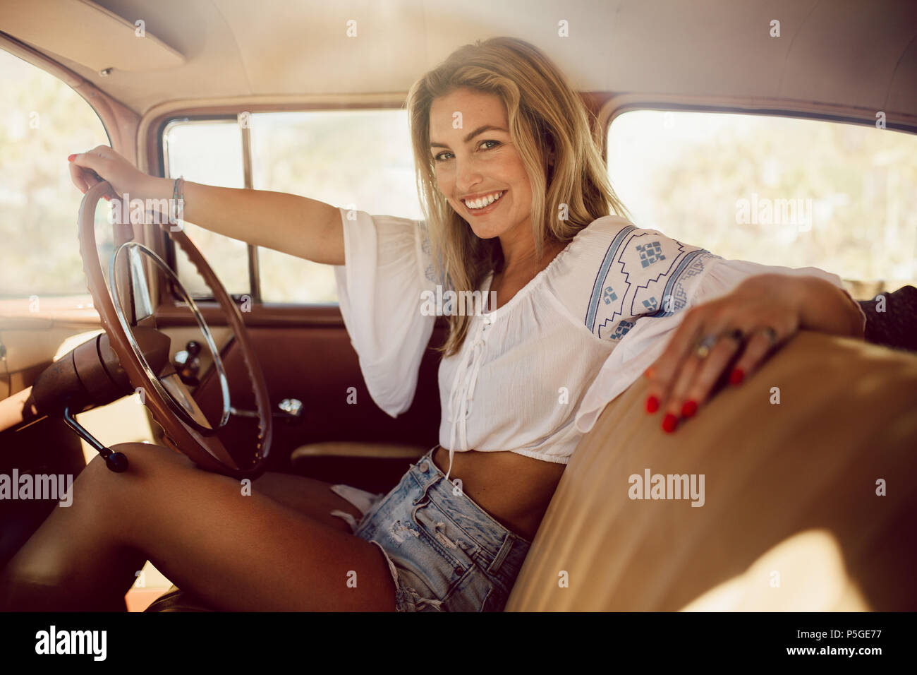 Ritratto di bella donna che viaggiano in un'auto d'epoca. Femmina caucasica alla guida di una vettura vecchia. Foto Stock