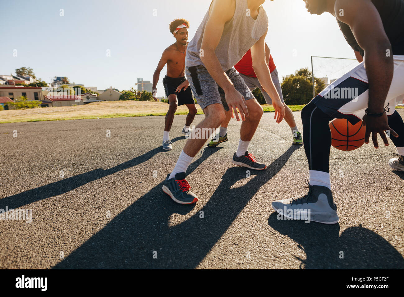 Gli uomini la riproduzione di gioco di basket in una giornata di sole. Gli uomini praticano abilità di basket in area di gioco. Foto Stock
