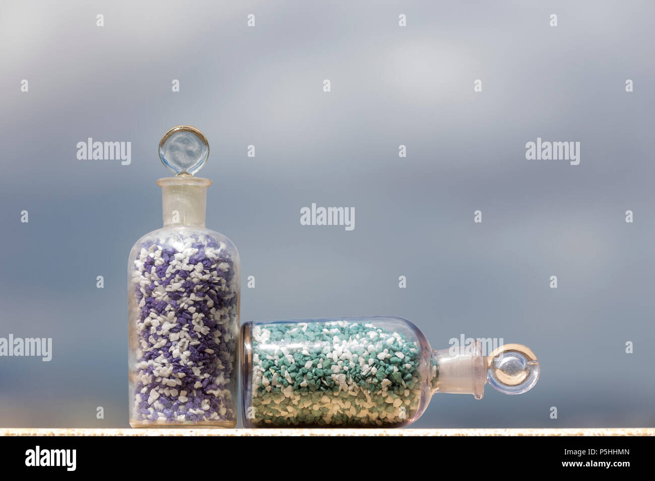 Bottiglie di vetro con pietre colorate, a giacente Foto Stock