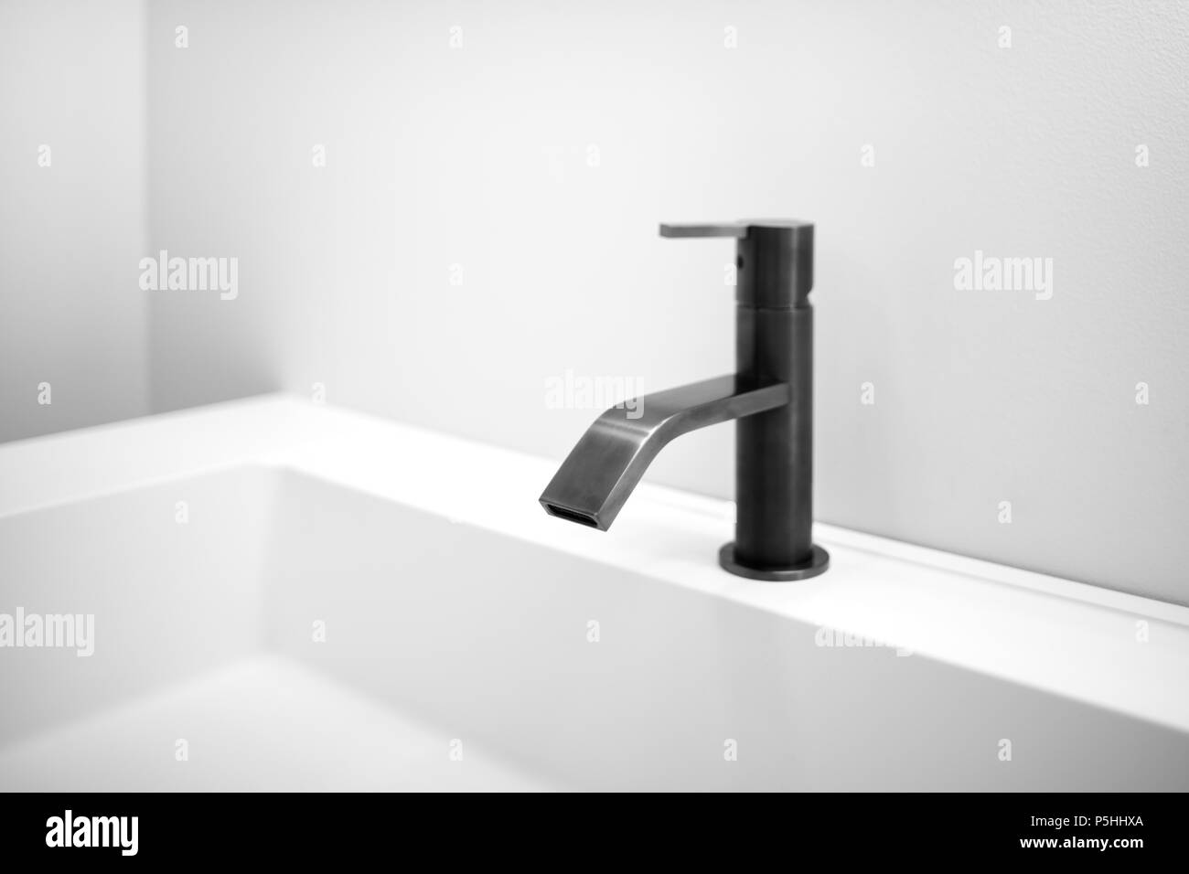 Bagno bianco grigio interno con lavabo bianco e close-up black moderno stile techno rubinetto Foto Stock
