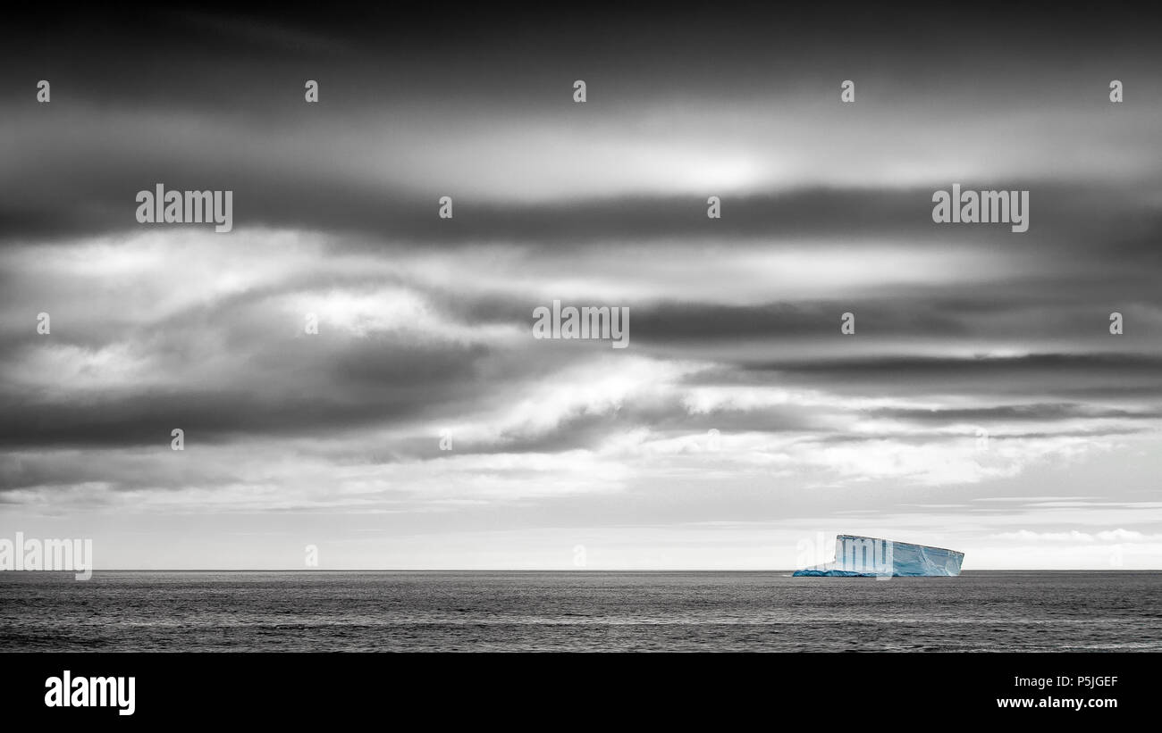 Iceberg solitario nell'Oceano del Sud sotto il cielo in tempesta Foto Stock