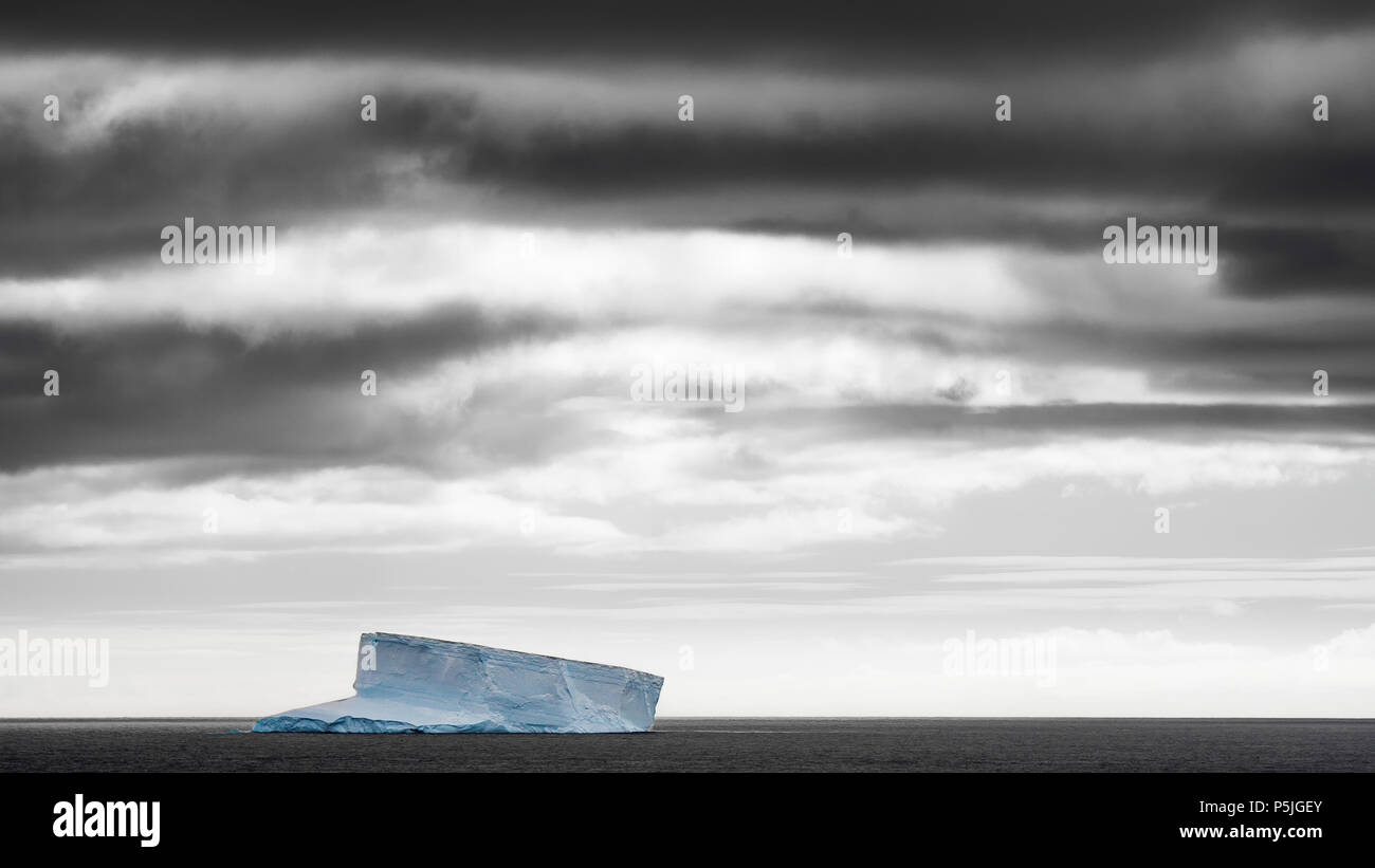 Iceberg solitario nell'Oceano del Sud sotto il cielo in tempesta Foto Stock