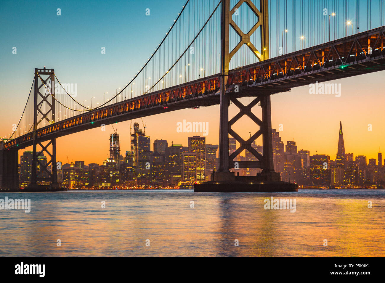 Classic vista panoramica dello skyline di San Francisco con il famoso Oakland Bay Bridge illuminato nel bellissimo golden luce della sera al tramonto in estate Foto Stock