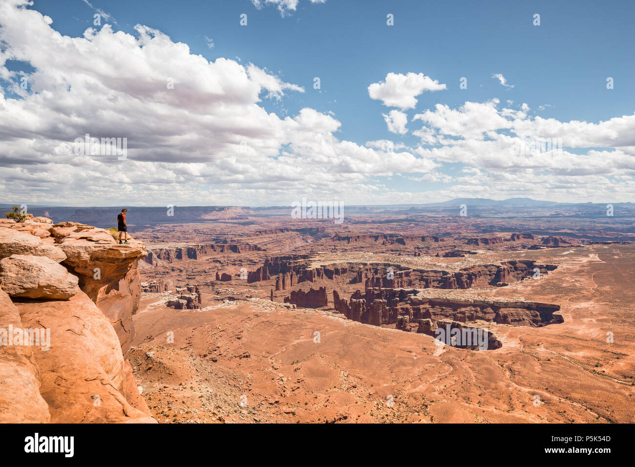 Un maschio di un escursionista è in piedi sul bordo di una scogliera godendo di una drammatica si affacciano di paesaggio panoramico nel bellissimo Parco Nazionale di Canyonlands, Utah, Stati Uniti d'America Foto Stock