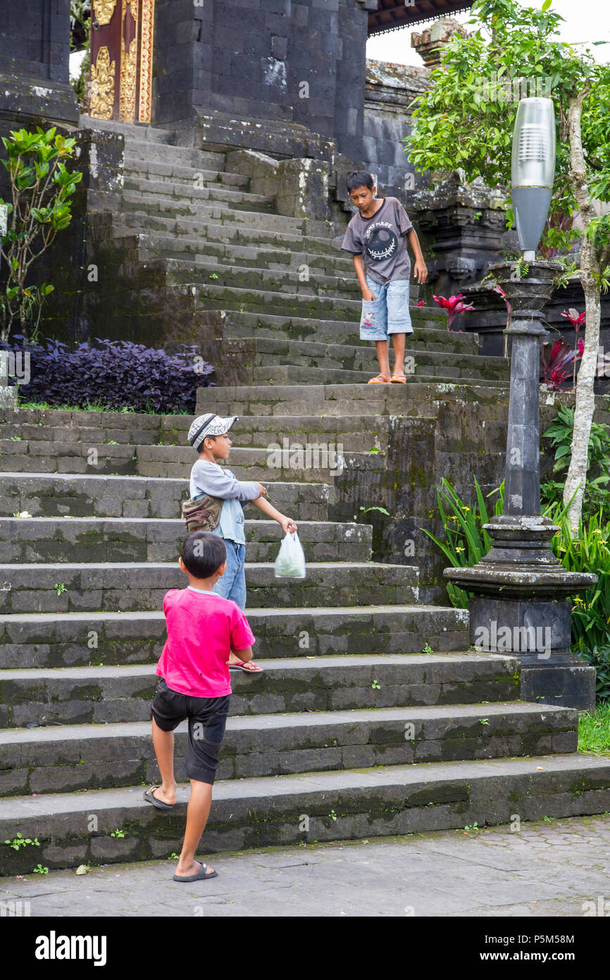 Ragazzi giocare sui gradini del tempio Besakih, appollaiato 1000m alto sulle pendici sud-occidentale del Monte Agung, Bali (anche Tempio Madre o Pura Besakih) Foto Stock