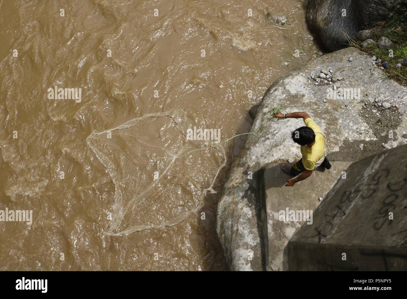 Un pescatore di buttare fuori la sua Tutina in rete per la cattura di pesci riverside nel nord del Kashmir Boniyar villaggio indiano in Kashmir controllato Foto Stock