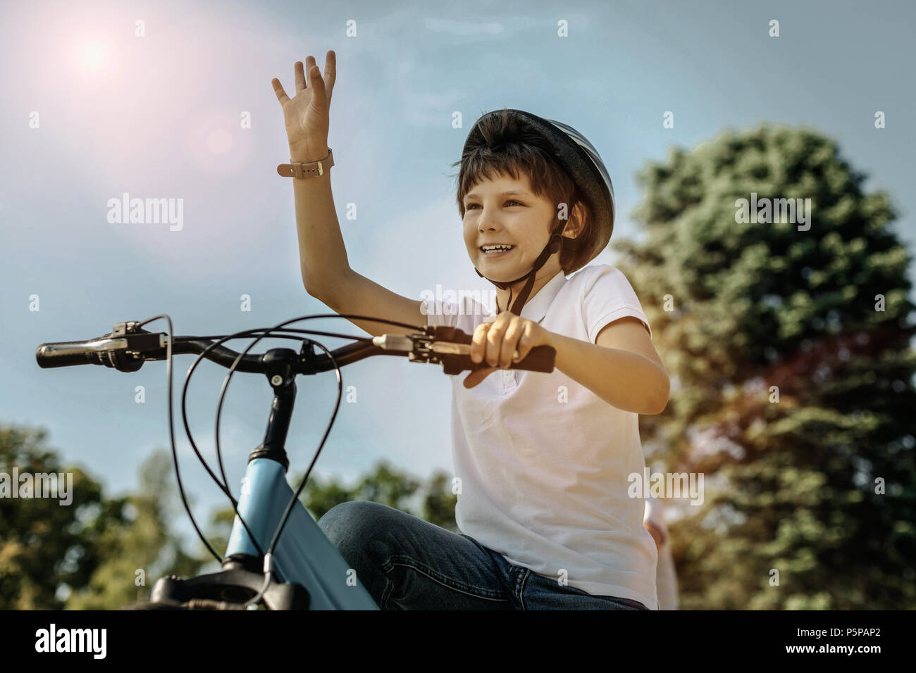 Felice ragazzo in sella alla sua bicicletta e ondulazione Foto Stock