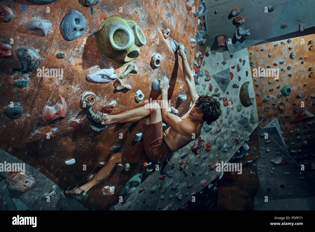Free climber giovane uomo artificiale di arrampicata boulder in ambienti interni Foto Stock
