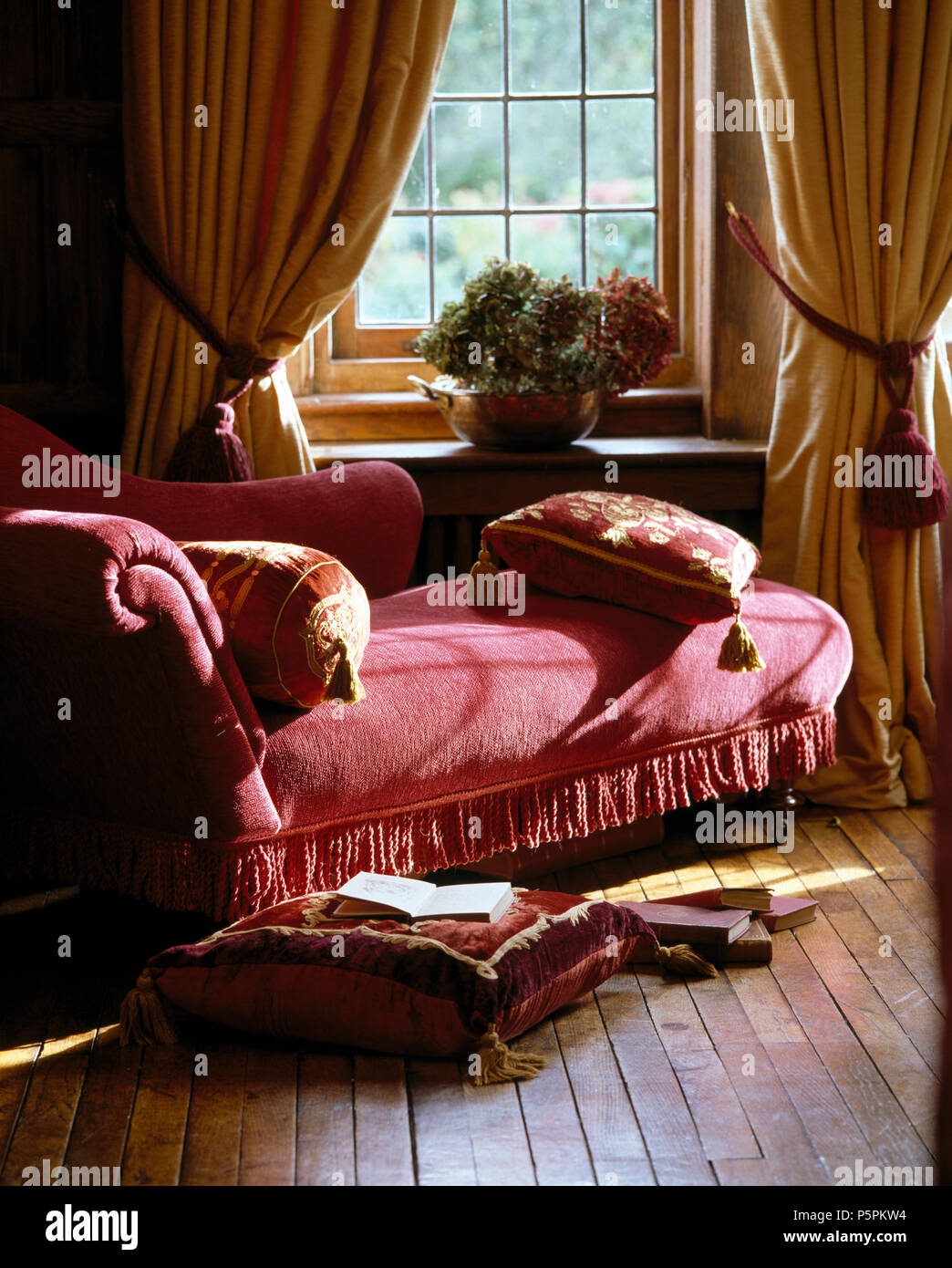 Ricco di cuscini di velluto rosso sulla chaise longue nella parte anteriore  della finestra con la crema piena tende nella camera da letto del paese  Foto stock - Alamy