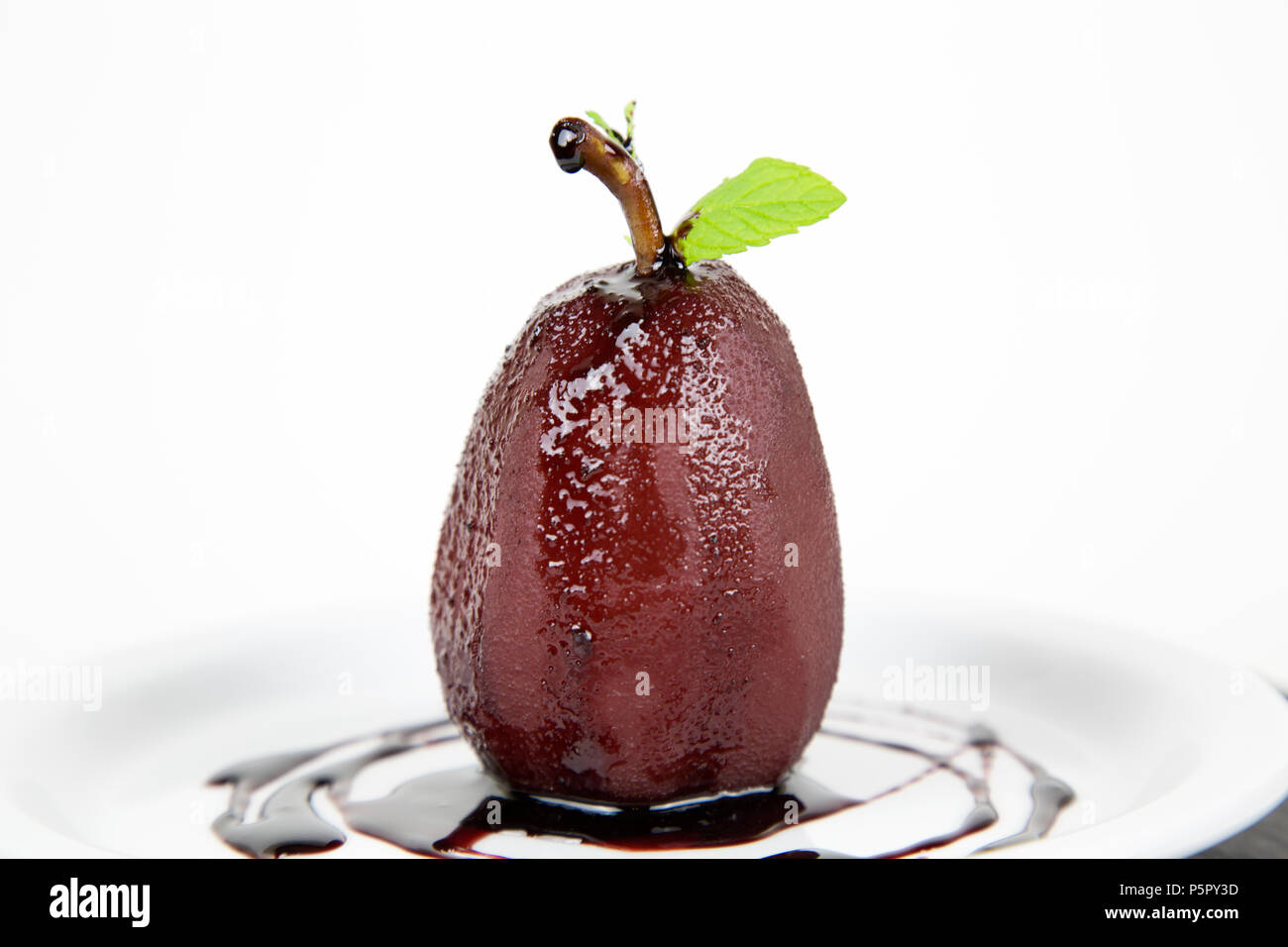 Pera affogata nel vino rosso e cannella sulla piastra Foto Stock