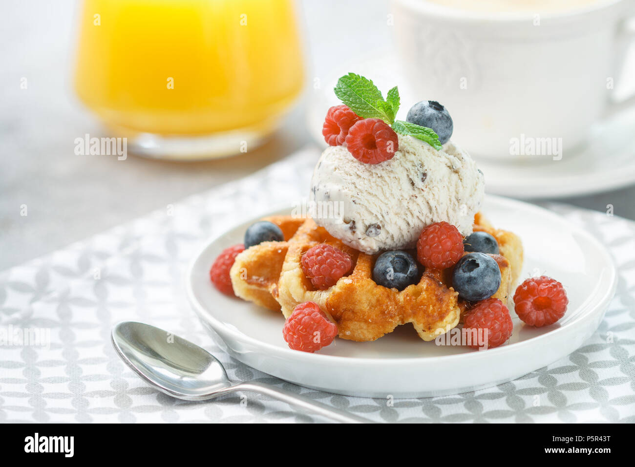 Waffles fatti in casa con gelato e frutti di bosco freschi-Lamponi  Mirtilli. Deliziosi dessert, cappuccino e succo di arancia sul tavolo. Foc  selettiva Foto stock - Alamy