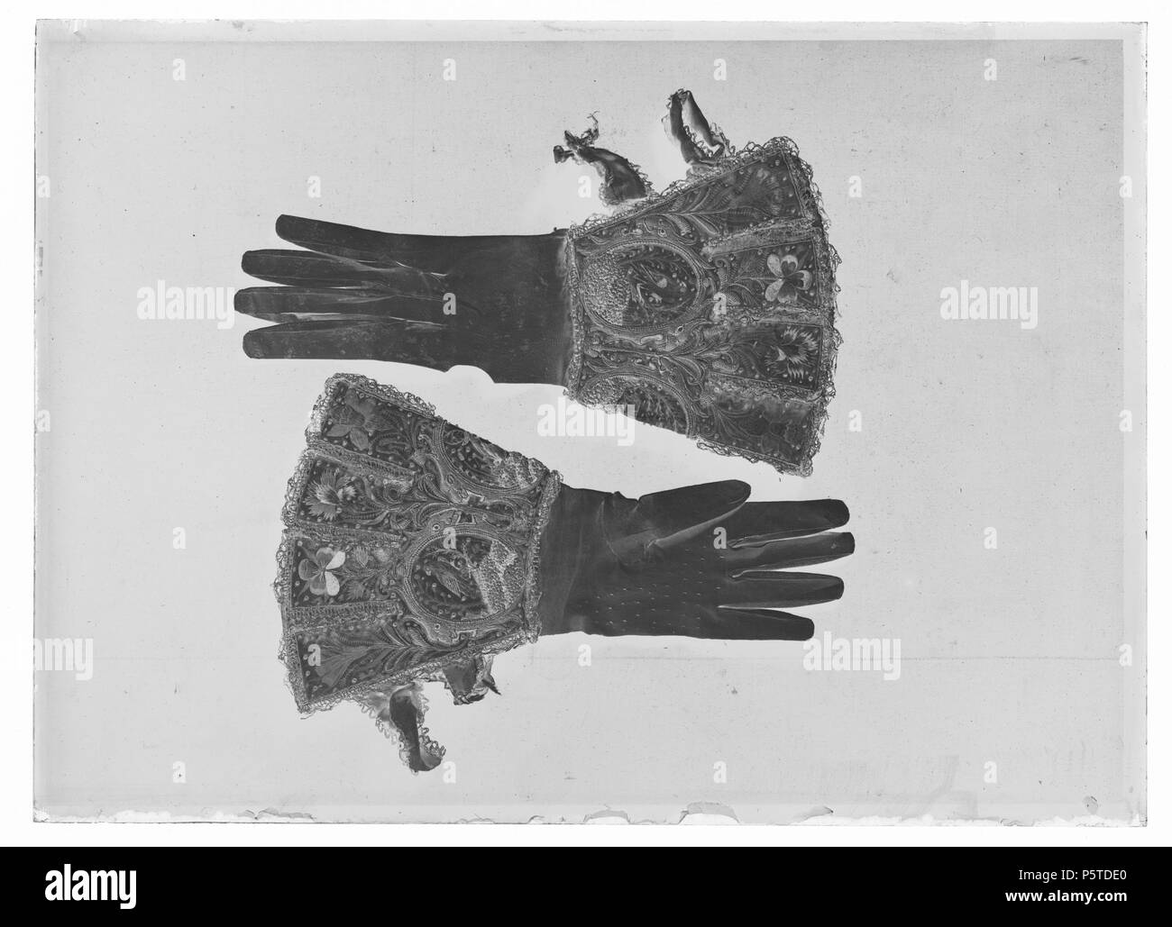 Broderad Kraghandske, ca1610. Svenska: av Handske vitt glacéskinn med stor krage broderad med silke mi många färger samt med guldtråd, kantiljer och paljetter. Kragens nedre del är utformad med medaljonger ho vilka brodeats olika djur.Mellan medaljongerna växer stjälkar fram som avslutas med naturalistiskt utformade blommor närmast kragens överkant: malva, pensée, nejlika och påsklilja. Blommorna avskiljs genom guldspets som delar in kragen ho kantiga flikar. Skinnet Själva är dock inte uppklippt. Ho 1867 års Livrustkammarinventarium har handskarna sammanförts med Karl X Gustavs kröningsdräkt. De Foto Stock