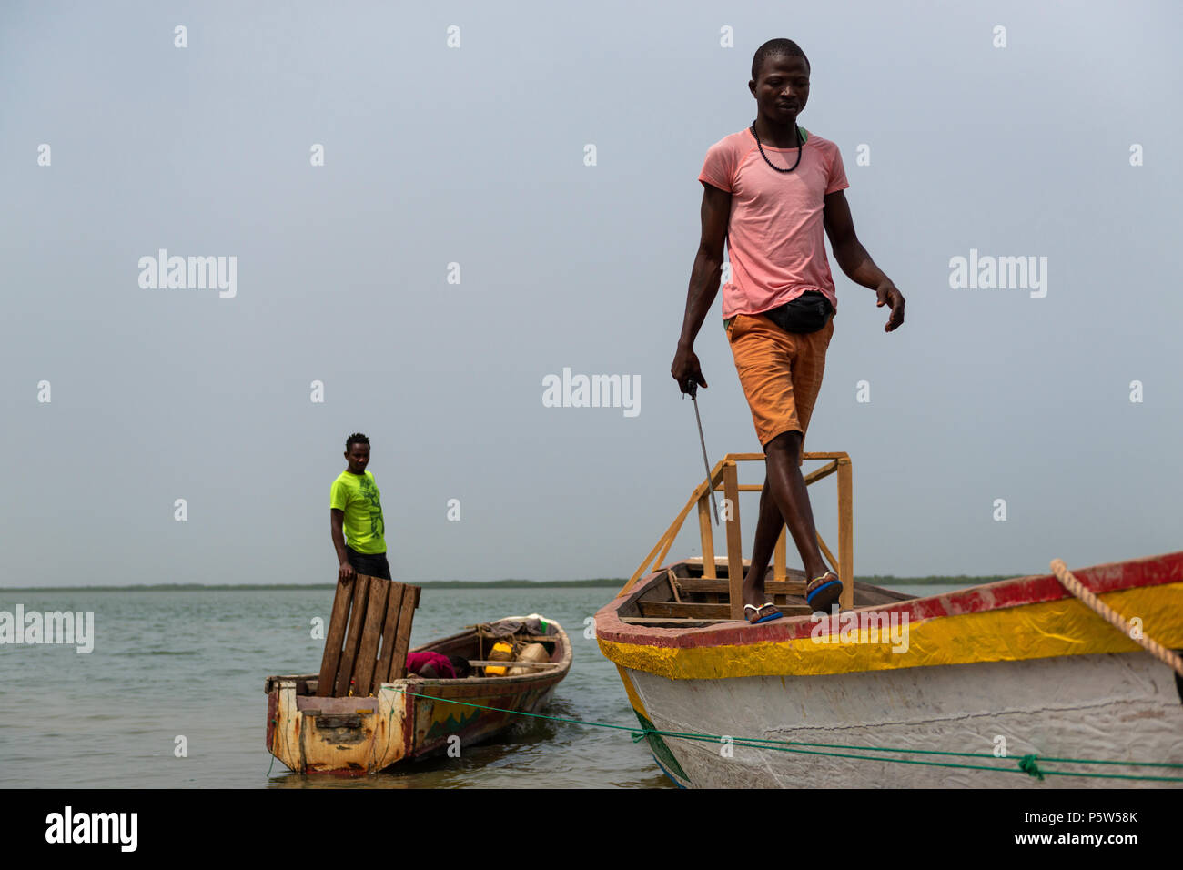 Cacheu, Repubblica di Guinea Bissau - 1 Febbraio 2018: i pescatori preparano le loro canoe nel porto della città di Cacheu in Guinea Bissau. Foto Stock