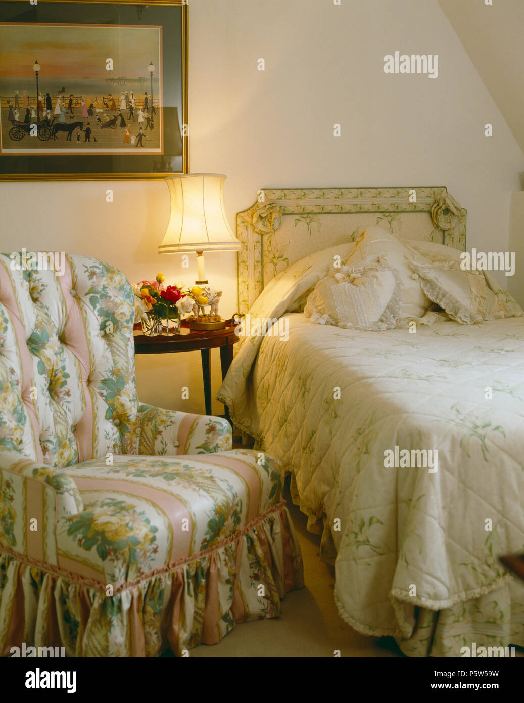 Poltrona imbottita in motivi floreali e rosa tessuto a righe nella piccola  camera da letto con lampada accanto a letto singolo con testiera imbottita  Foto stock - Alamy