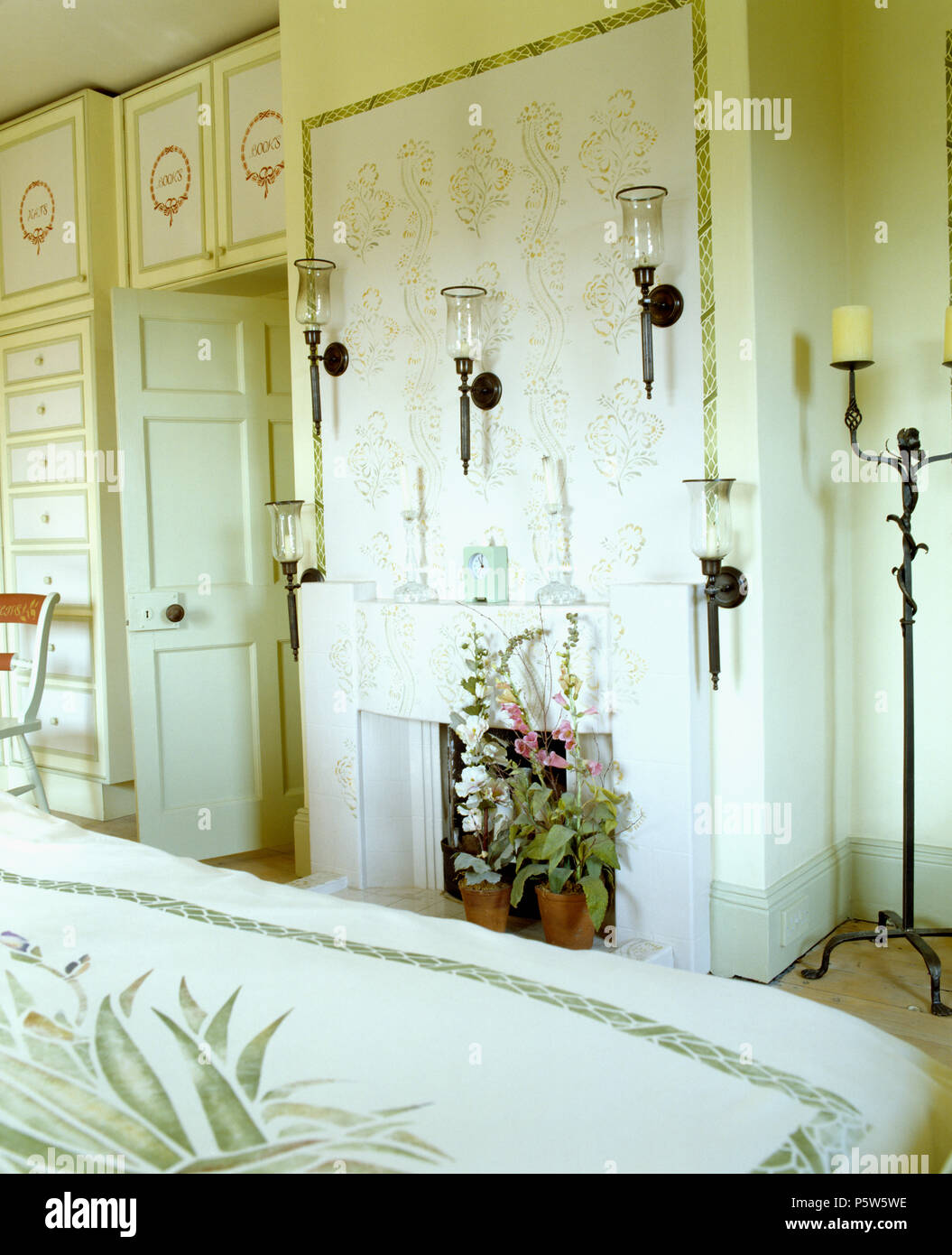 Candelabri a muro con lanterne di vetro impresse sulla parete sopra il camino in camera da letto del paese Foto Stock