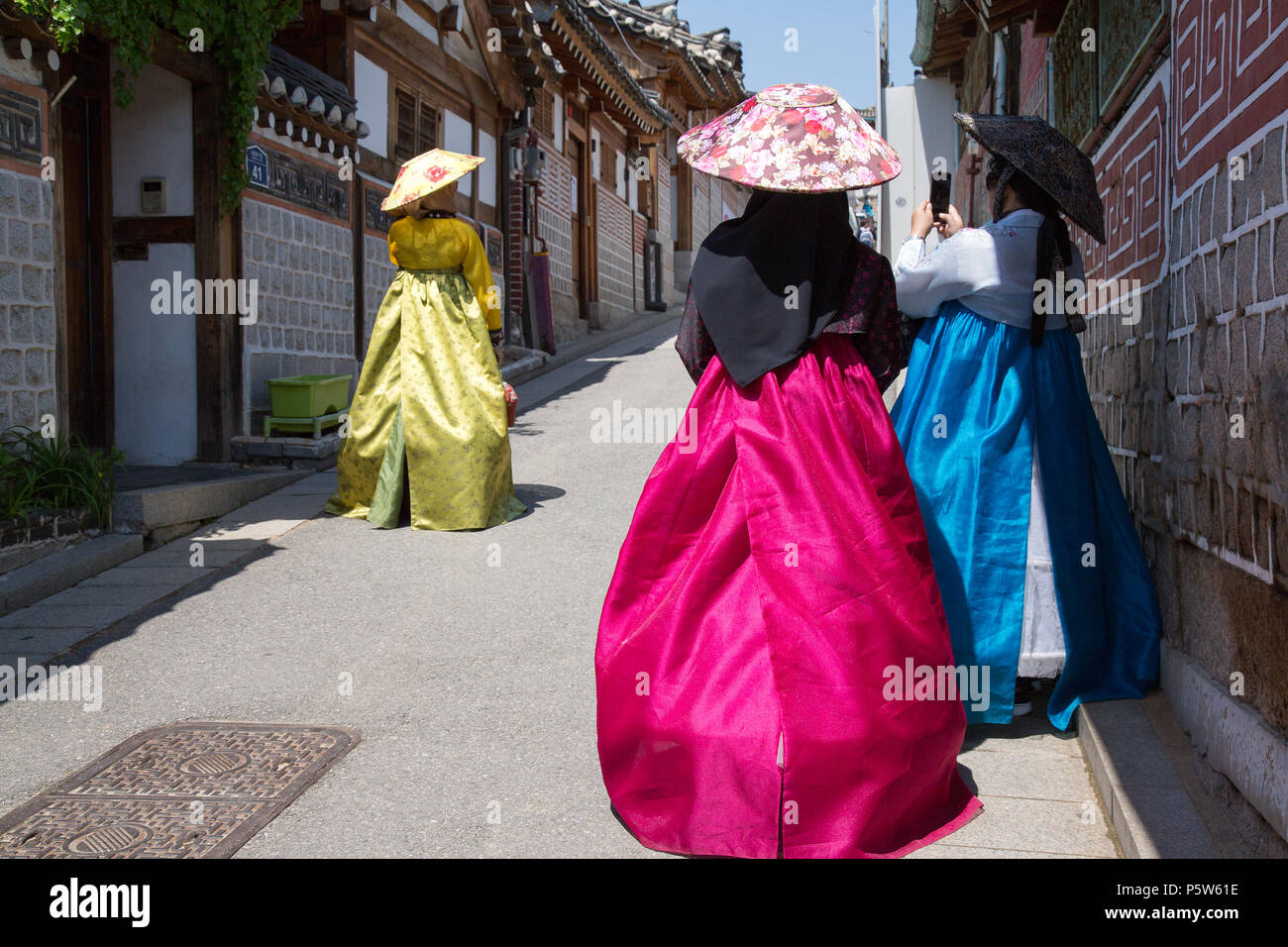 Donne vestiti in abiti tradizionali a piedi attraverso il villaggio di Bukchon Hanok, Seul. Foto Stock