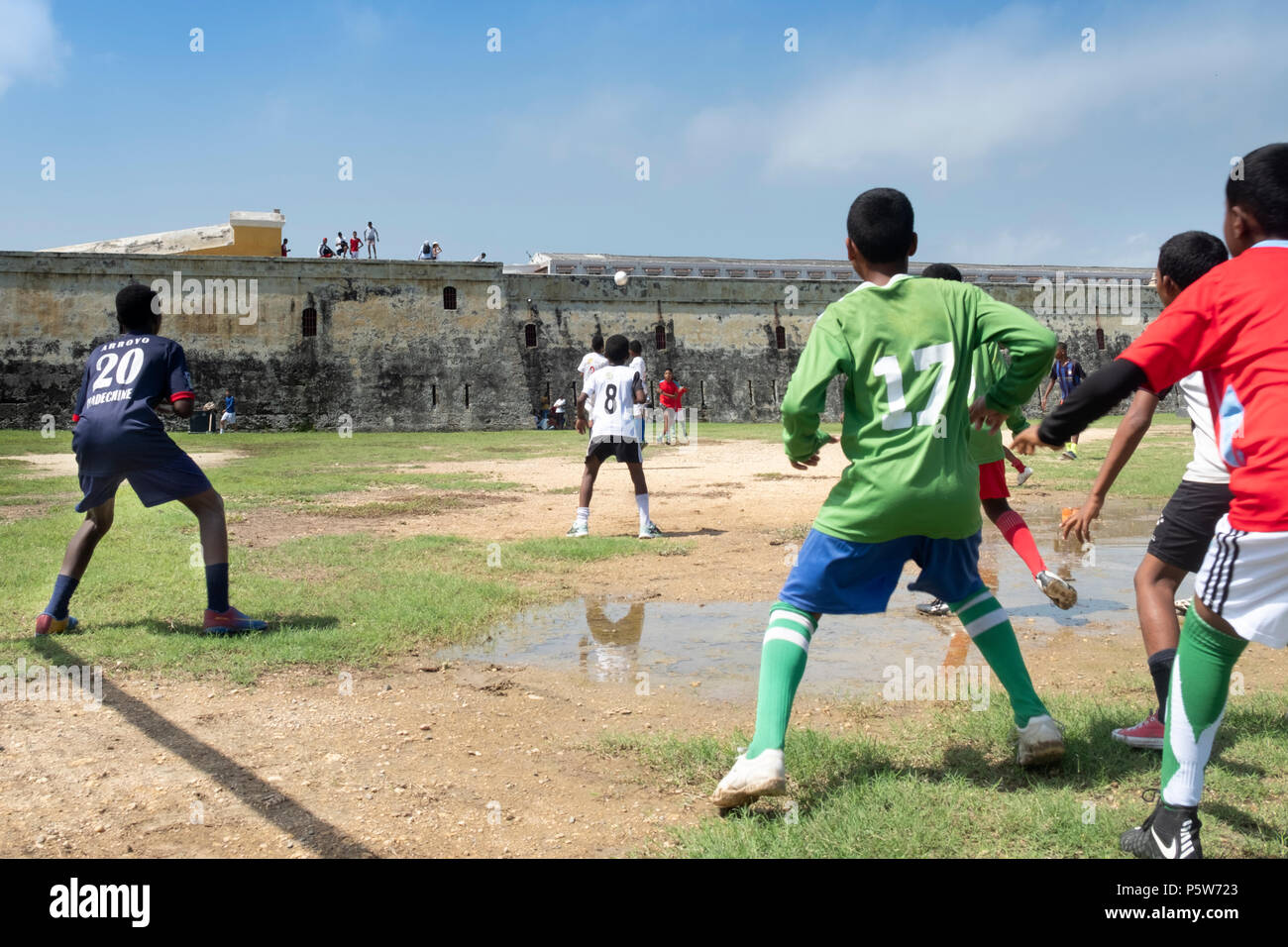 Colombia, Cartagena, i bambini locali che giocano a calcio vicino al vecchio muro fortificato della città coloniale spagnola. Foto Stock