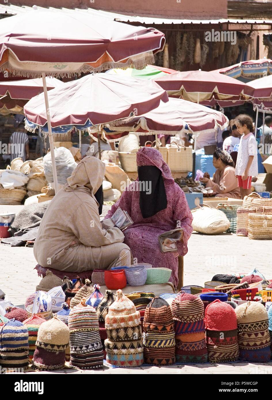 Zoco, Marrakech. . . Zoco mercado mercato tipico tipico tradizionale tradicional compra compras shoping tienda tiendas stallo. . Mujer mujeres donna burka calle street sombrilla sombrillas ombrellone sombrero mercancia sombreros hat. . Medina. Foto Stock