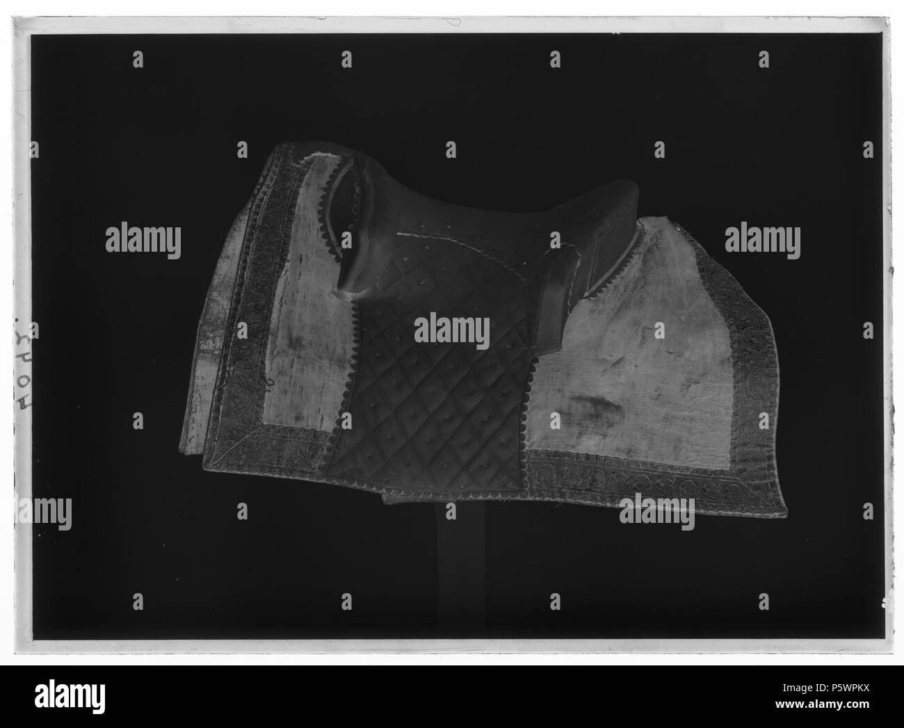 Bomsadel. Svenska: Sadel med rektangulära kappor klädda med sammet röd och fodrade med svartmålad väv, på utsidan kantade med allevati guldgalon. Siede och bommar överklädda med ljust sämskskinn samt mönsterstickningar med gult silke.Frambom, tvådelad ca 450 mm allevati, 90 mm hög, bakbom 550 mm allevati 65 mm hög. Sitsens sidor med stickning ho rutmönster samt sämskskinnet neddraget fino a kappans kant. Bom överklädd väv med. Bossor klädda med naturfärgat linne, fodrade med scotto läder och kantade med vitt skinn.Fyra stroppar för sadelgjord. Två krampor av stål för stigläder. . Data sconosciuta. N/A 219 Bomsade Foto Stock
