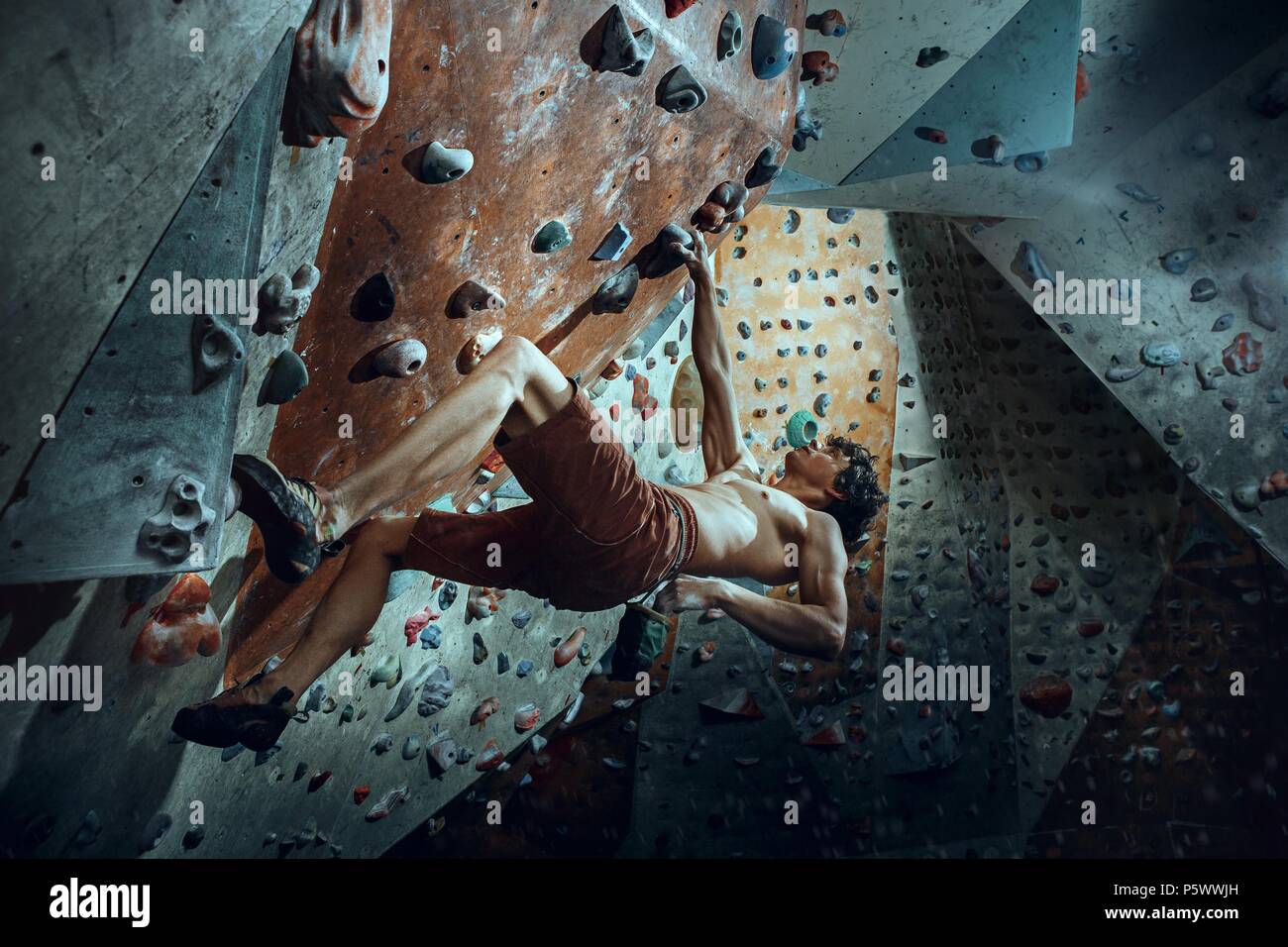 Free climber giovane uomo artificiale di arrampicata boulder in ambienti interni Foto Stock