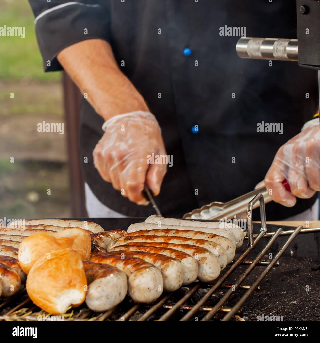 Mani uomo, salsicce di cottura sul grill caldo Foto Stock