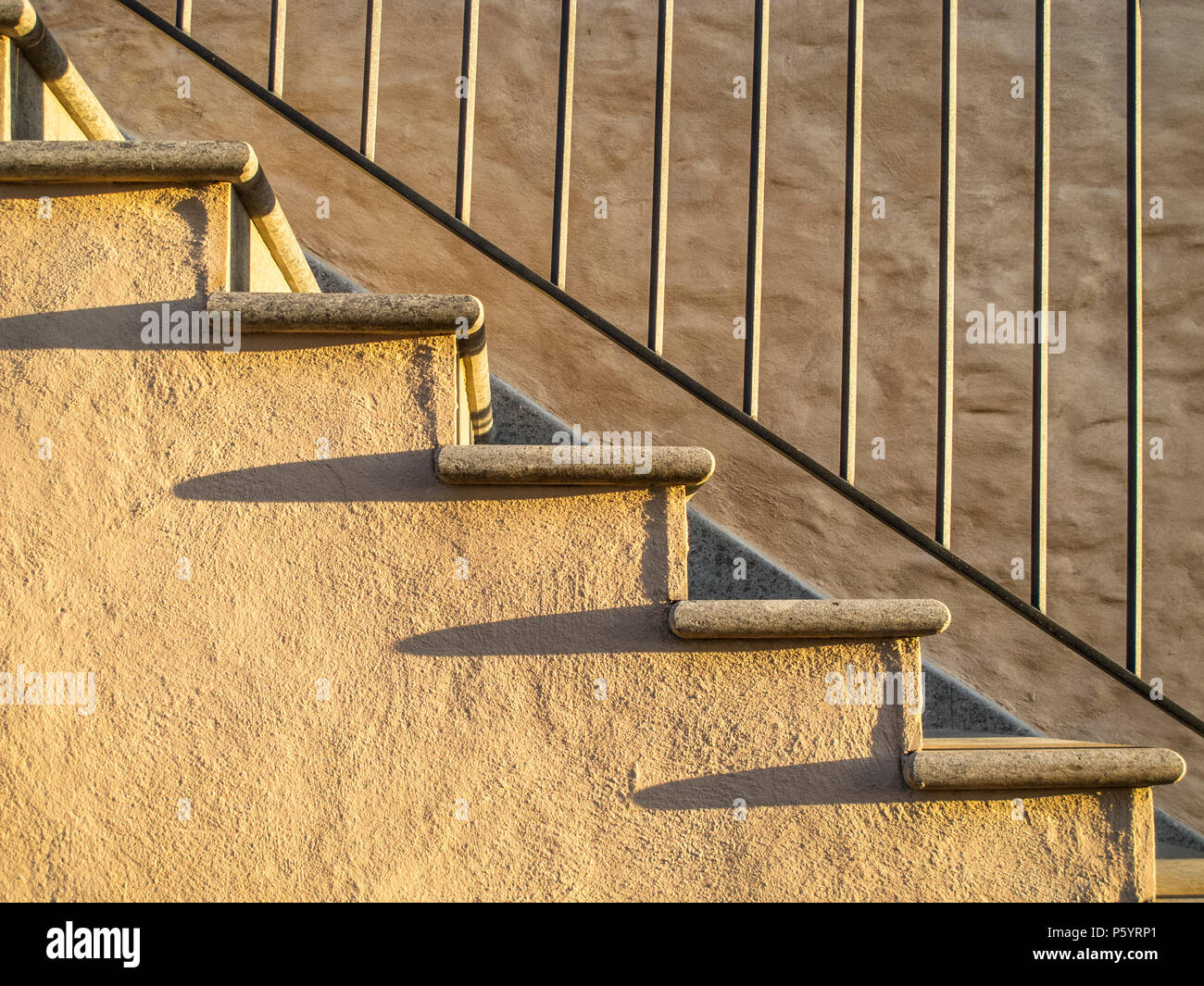Scale in muratura con ringhiera in ferro e lunghe ombre sui gradini Foto Stock