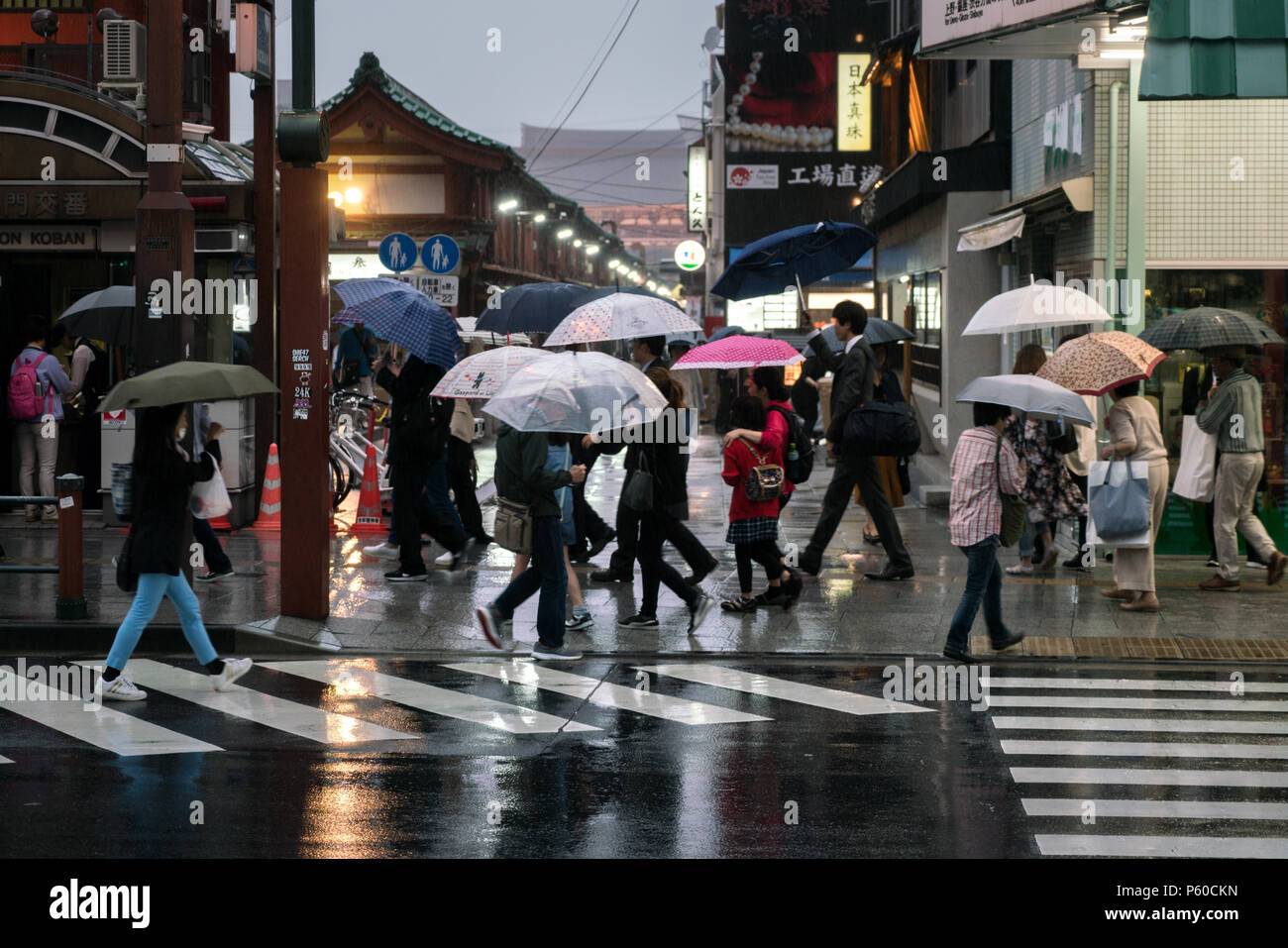 TOKYO, Giappone - 23/5/2018: Persone con ombrelloni a camminare su una strada bagnata sul giorno di pioggia. Foto Stock