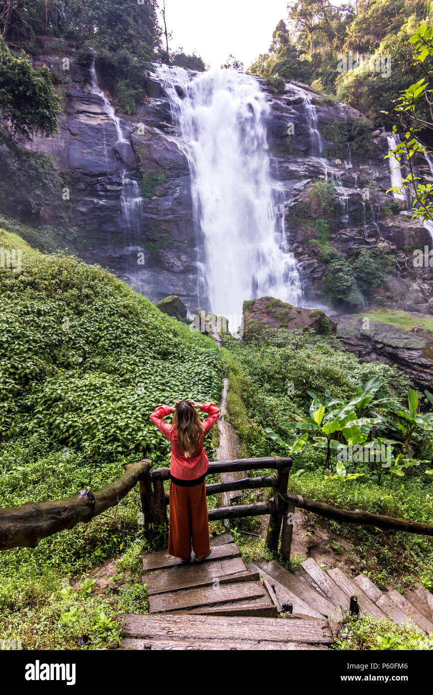 Ragazza in piedi nella foresta vicino enorme cascata nella giungla della Thailandia Foto Stock