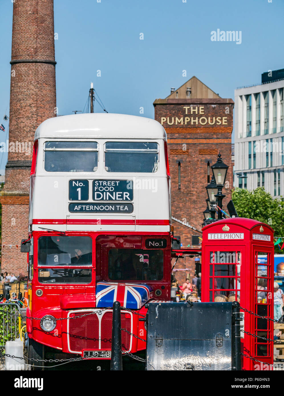 Tradizionale in rosso London bus e British telefono rosso scatola, Albert Dock, Liverpool, in Inghilterra, Regno Unito con mattoni Pumphouse pub e la torre in mattoni in background Foto Stock