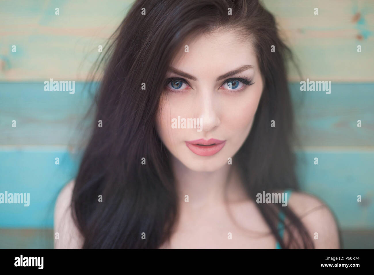 Ritratto di bella ragazza caucasica con capelli belli con gli occhi blu sul colorato sfondo di legno Foto Stock