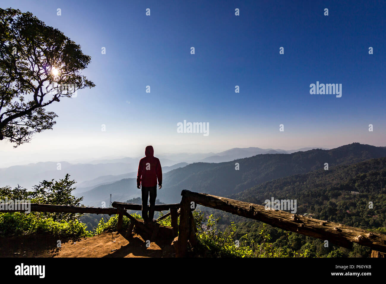Uomo in piedi sulla roccia al tramonto con le montagne al di sotto di Foto Stock