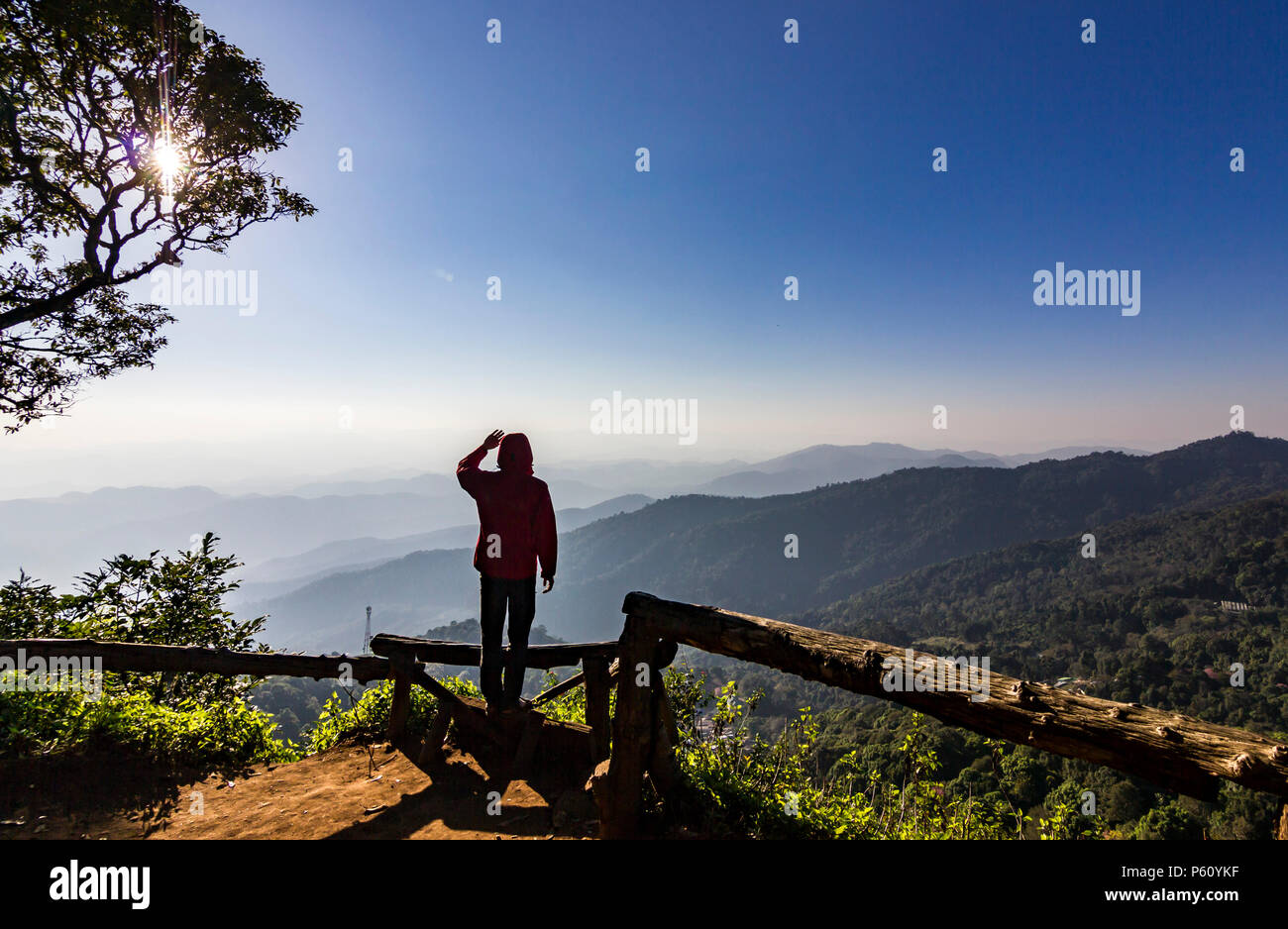 Uomo in piedi sulla roccia al tramonto con le montagne al di sotto di Foto Stock
