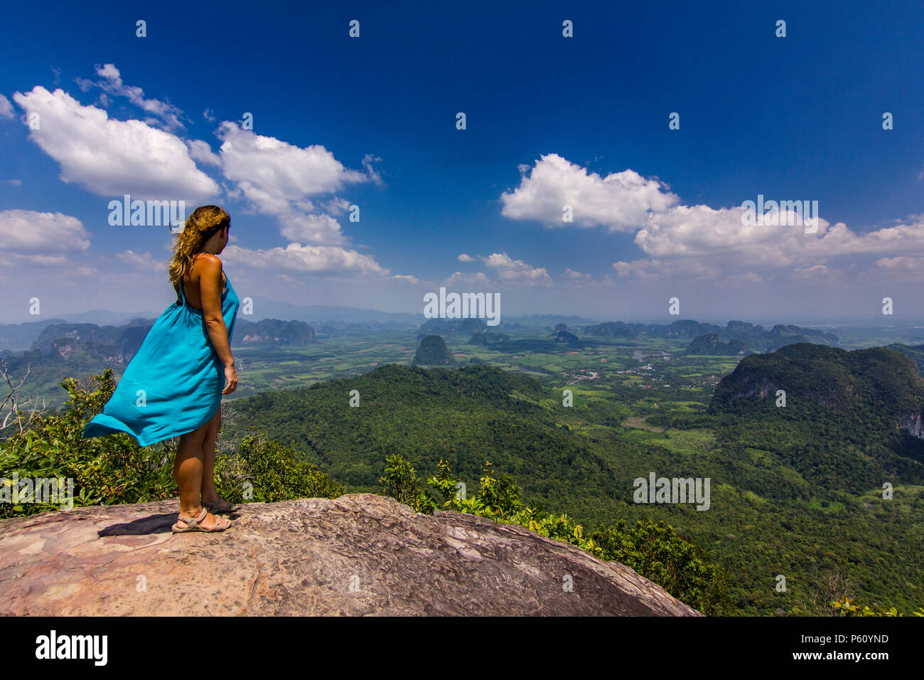 La ragazza con le mani fino in piedi sulla roccia al tramonto con le montagne al di sotto di Foto Stock