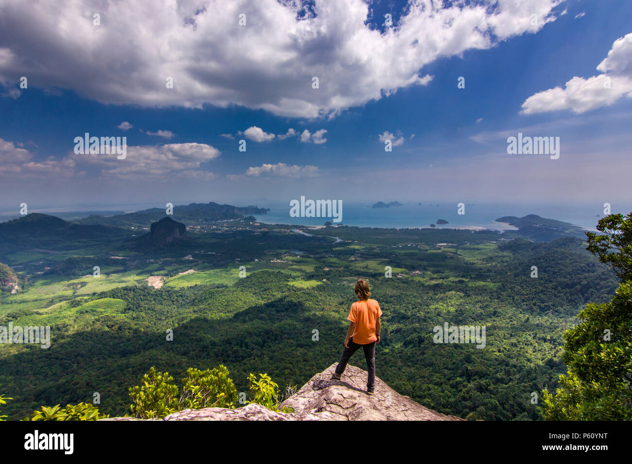 Uomo in piedi sulla roccia al tramonto con le montagne al di sotto di Foto Stock