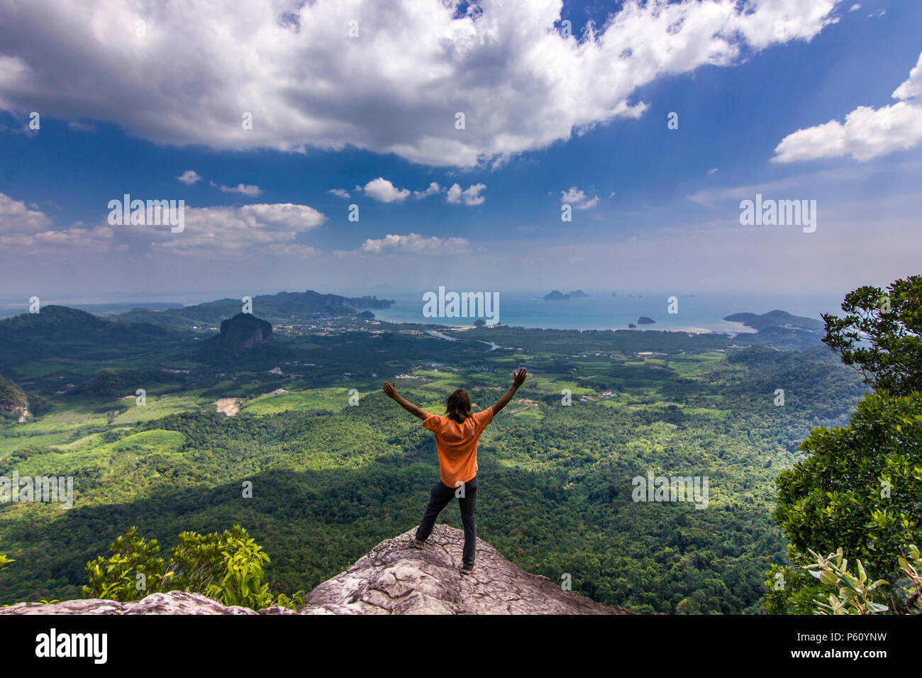 Uomo in piedi sulla roccia al tramonto con le montagne al di sotto di Foto Stock