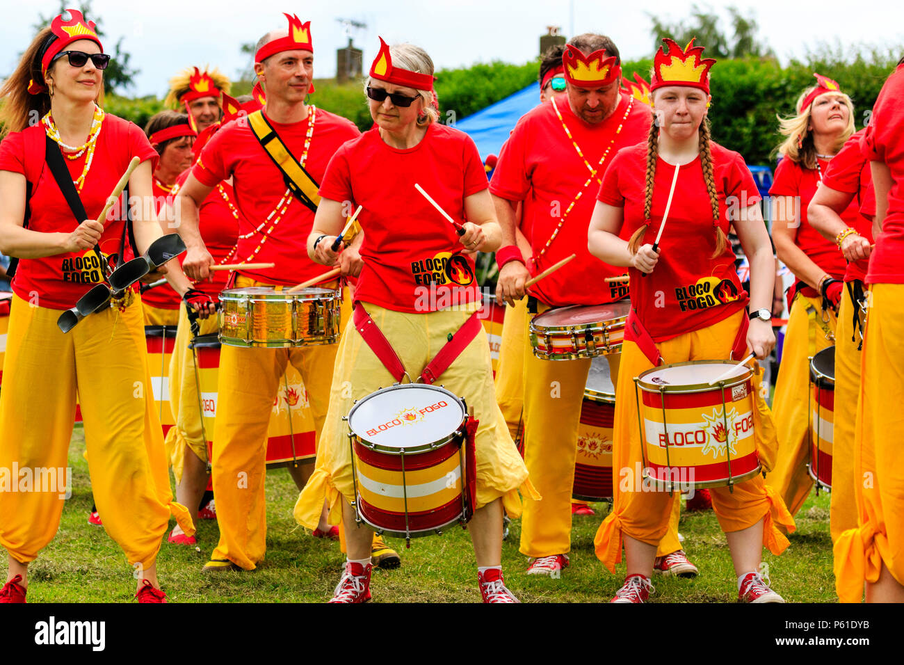 Bloco Fogo Sambra Drumming Band, al tortino di crema campionato, Coxhealth. Vestito di rosso e di giallo, fila di batteristi di fronte. Foto Stock