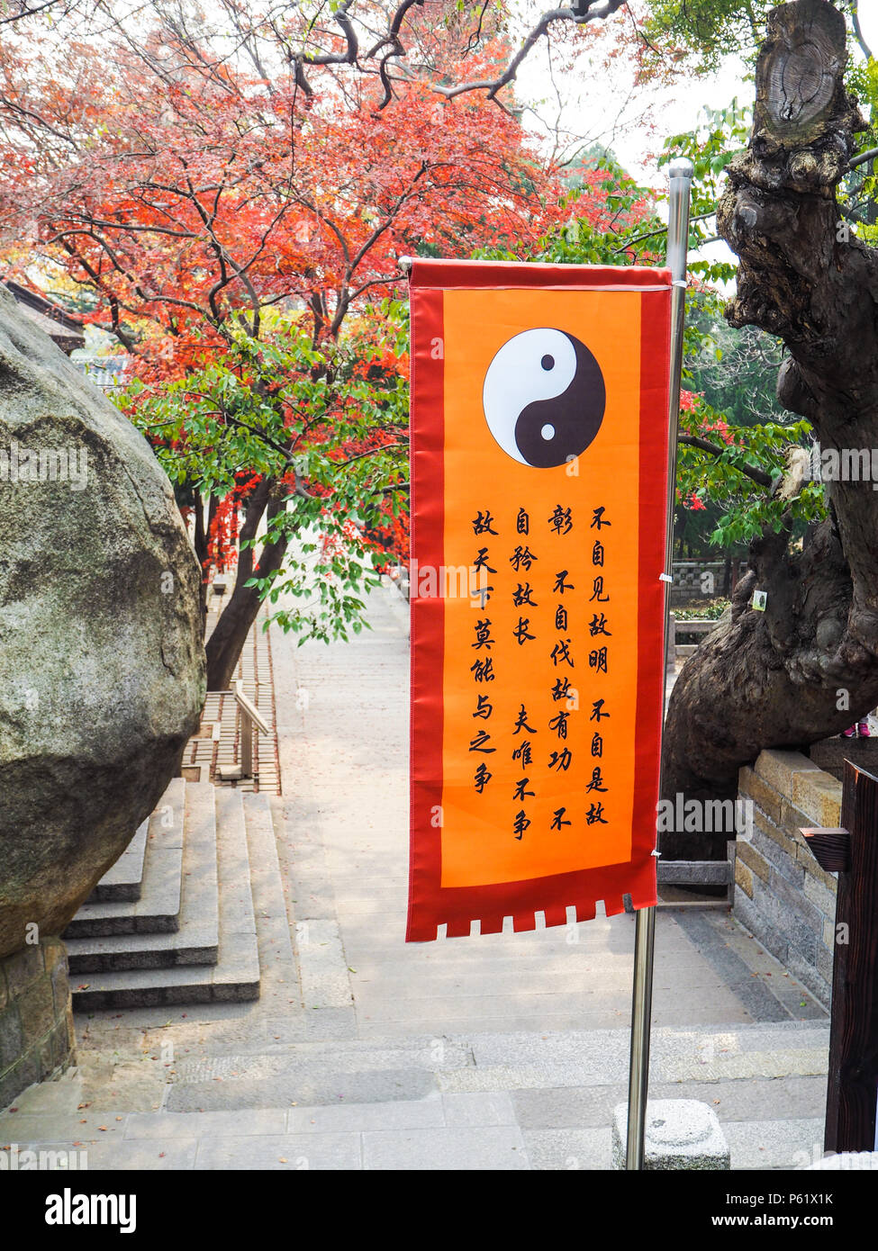QIngdao, Cina - Dicembre 2017: arancione brillante taoista di bandiera con yin yang simbolo nel cortile principale del Tempio Taiqing su Laoshan Foto Stock