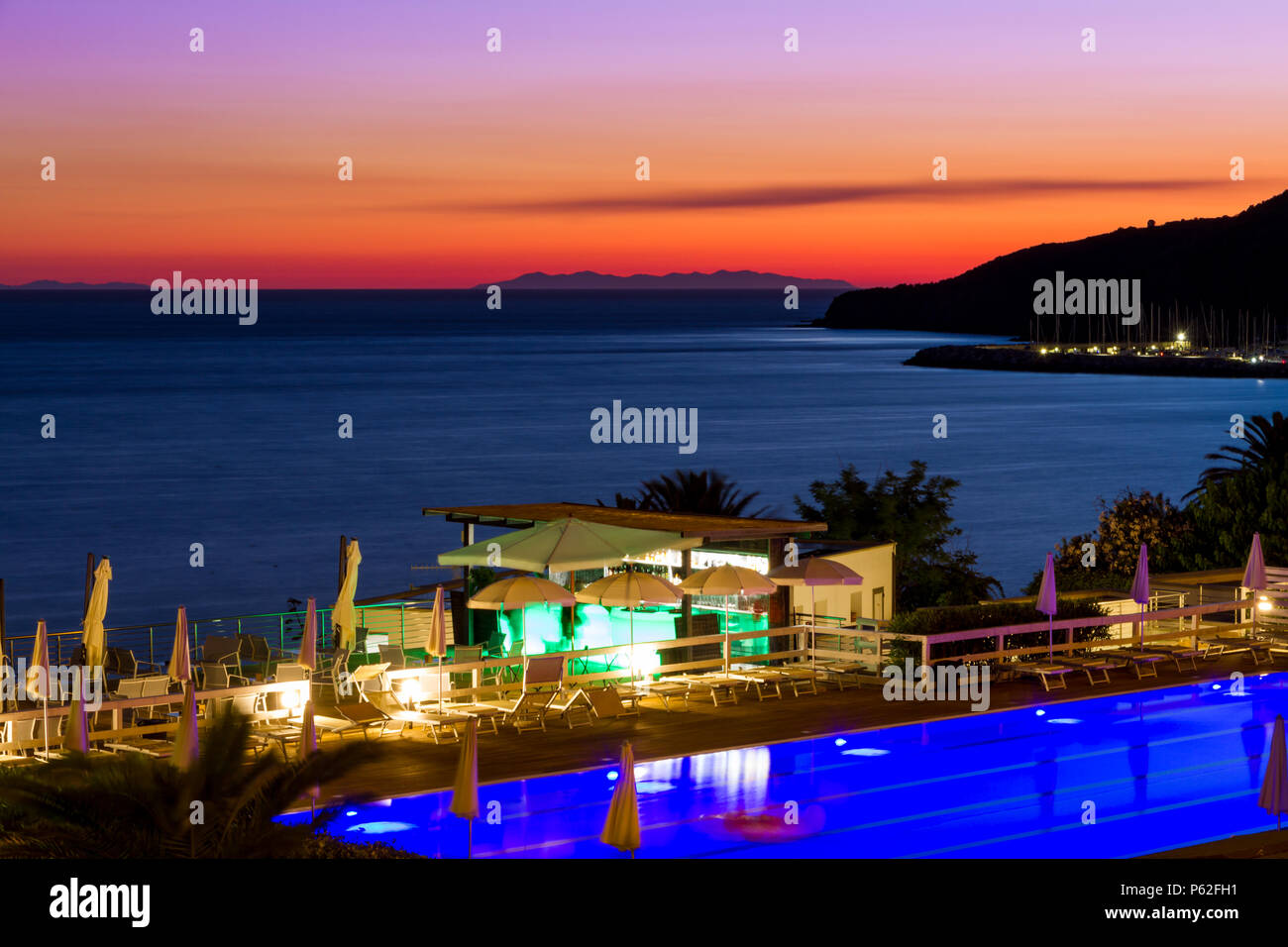 Una piscina e bar sul mare al tramonto in estate a Piombino di fronte all'Isola d'Elba, Italia Foto Stock
