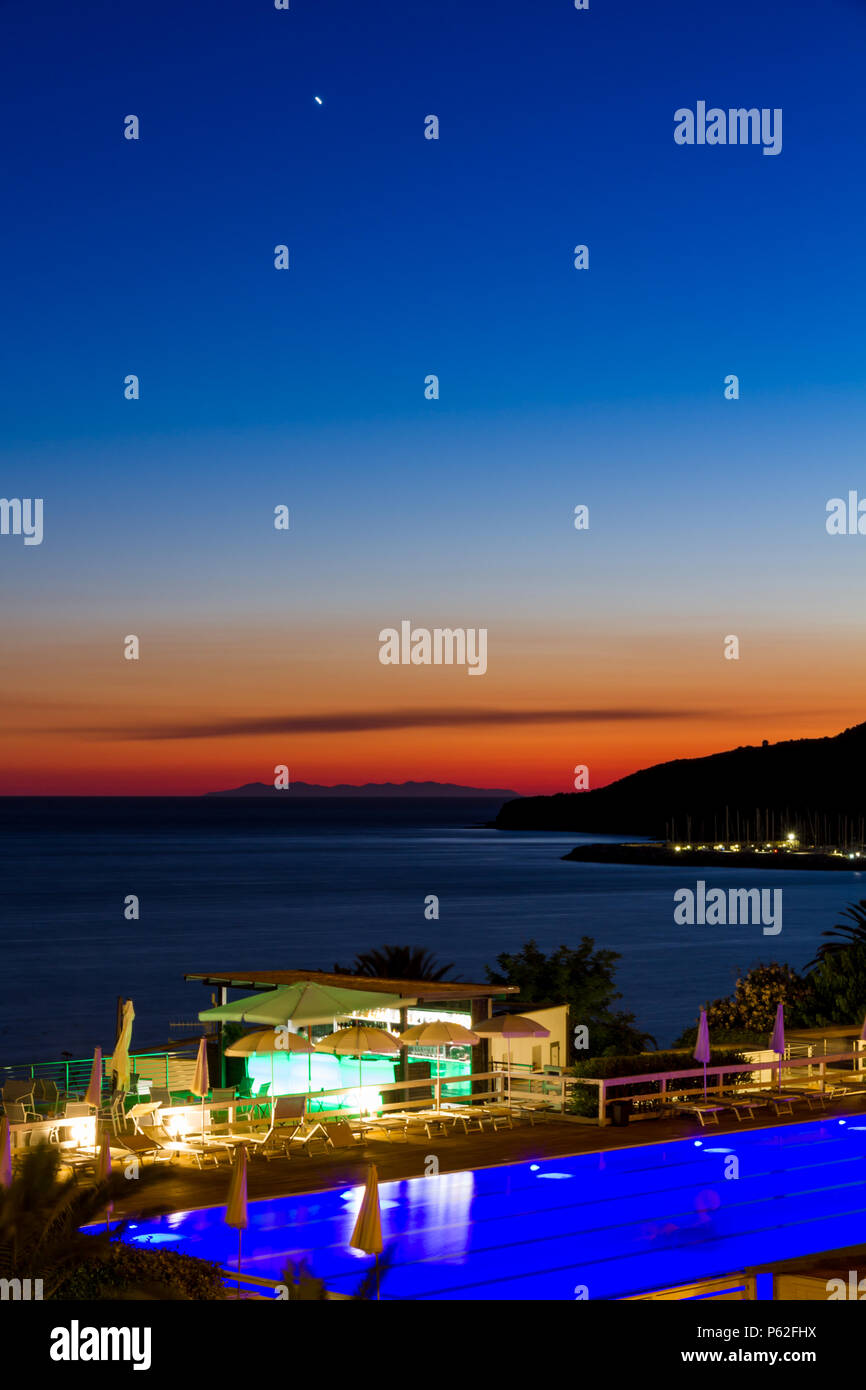 Una piscina e bar sul mare al tramonto in estate a Piombino di fronte all'Isola d'Elba, Italia Foto Stock