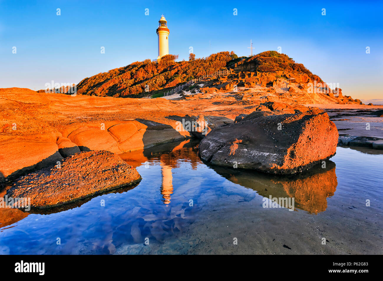 Poco profonda pozza di marea con rocce di arenaria sul promontorio plato di Norah testa con Norah faro nella calda luce del mattino contro blu cielo pulito. Foto Stock