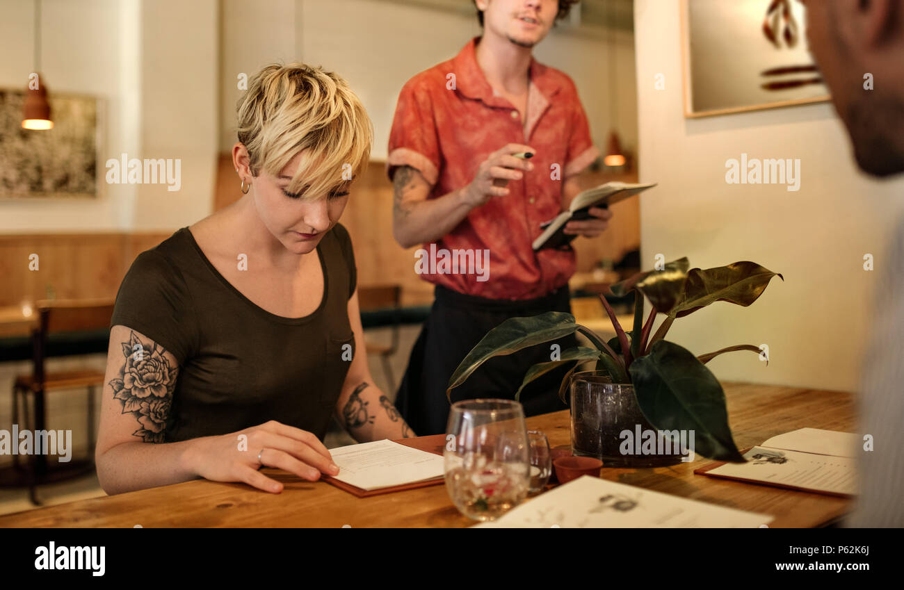 La donna la lettura del menu mentre seduti a un tavolo bistro Foto Stock