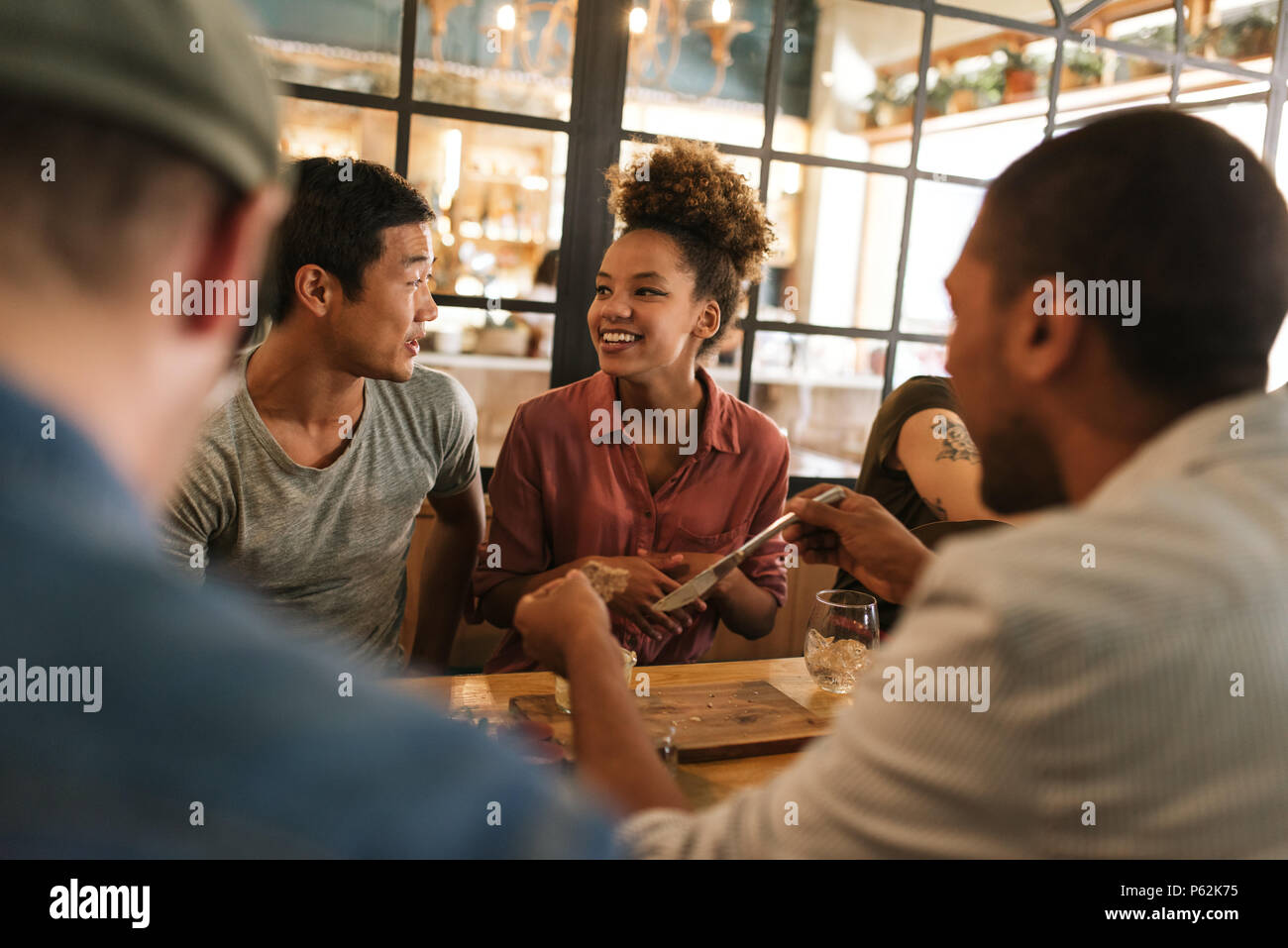 Sorridente giovani amici parlare insieme su un bistrò cena Foto Stock