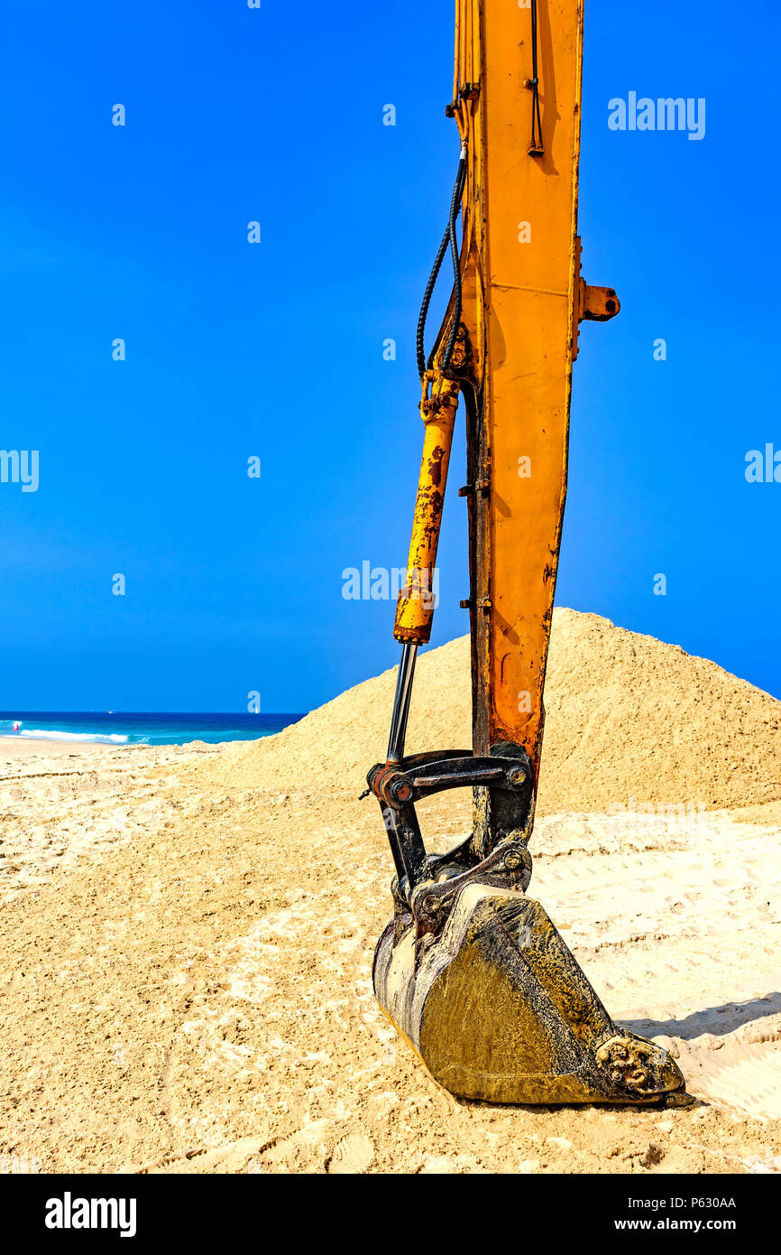 Escavatore giallo su sabbia in spiaggia in una giornata di sole Foto Stock