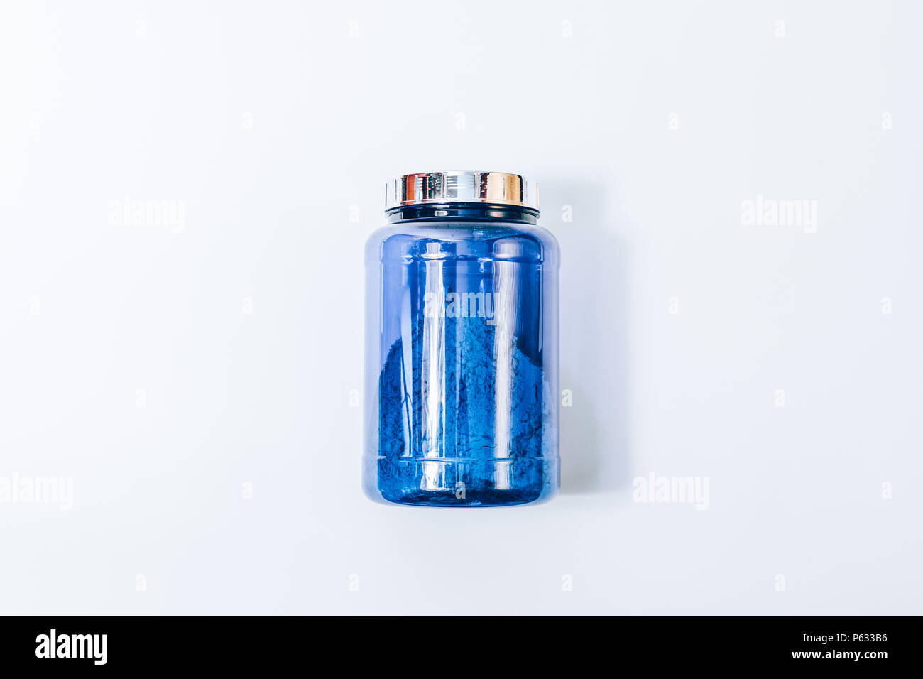 Big Blue jar di proteine in polvere, piatto laici. Immagine minima della banca di nutrizione sportiva supplementi, vista dall'alto su un solido bianco sullo sfondo. Foto Stock