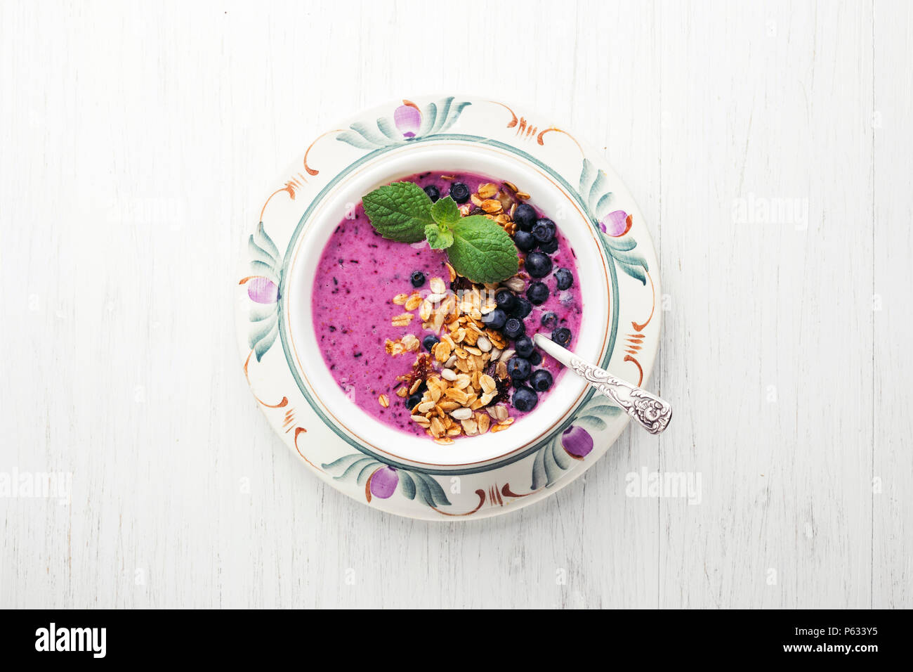 Ciotola frullato con muesli, mirtilli e menta su un tavolo di legno. Una sana prima colazione, vista dall'alto. Foto Stock