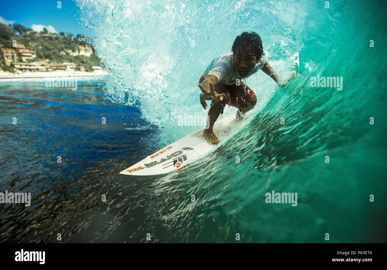 Surfista Balinese in sella alla canna del verde onda surf a Bingin, Bali Foto Stock