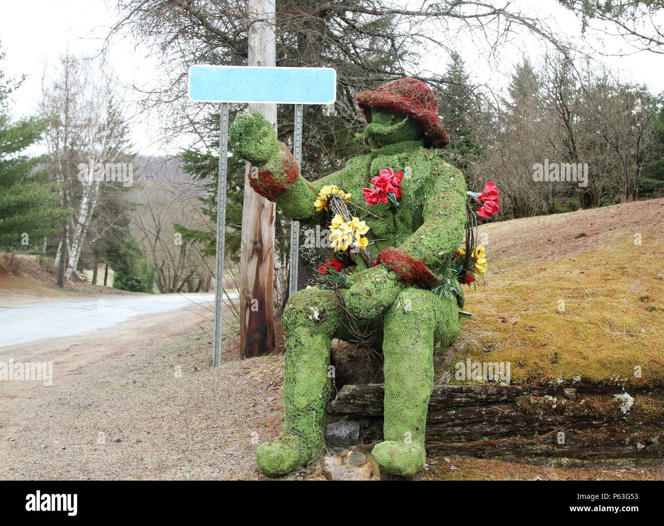 Verde e marrone scultura di un uomo coperto di muschio verde seduto su un tumulo di erba Foto Stock
